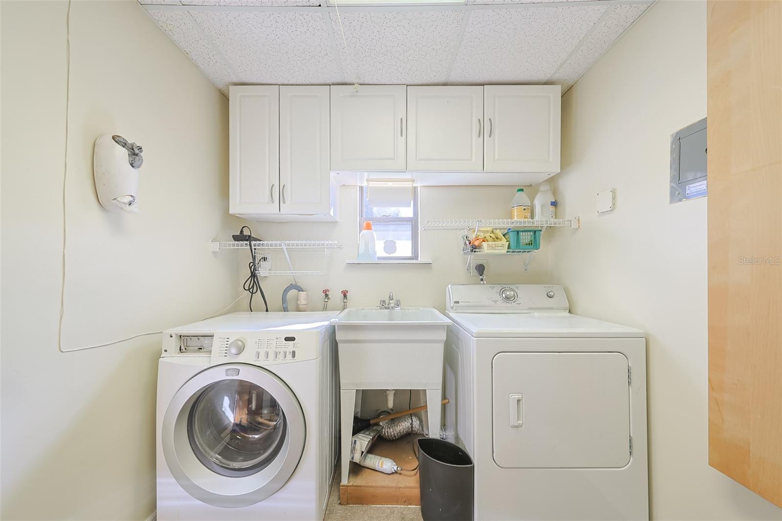 Super spacious laundry room with cabinet and shelves.
