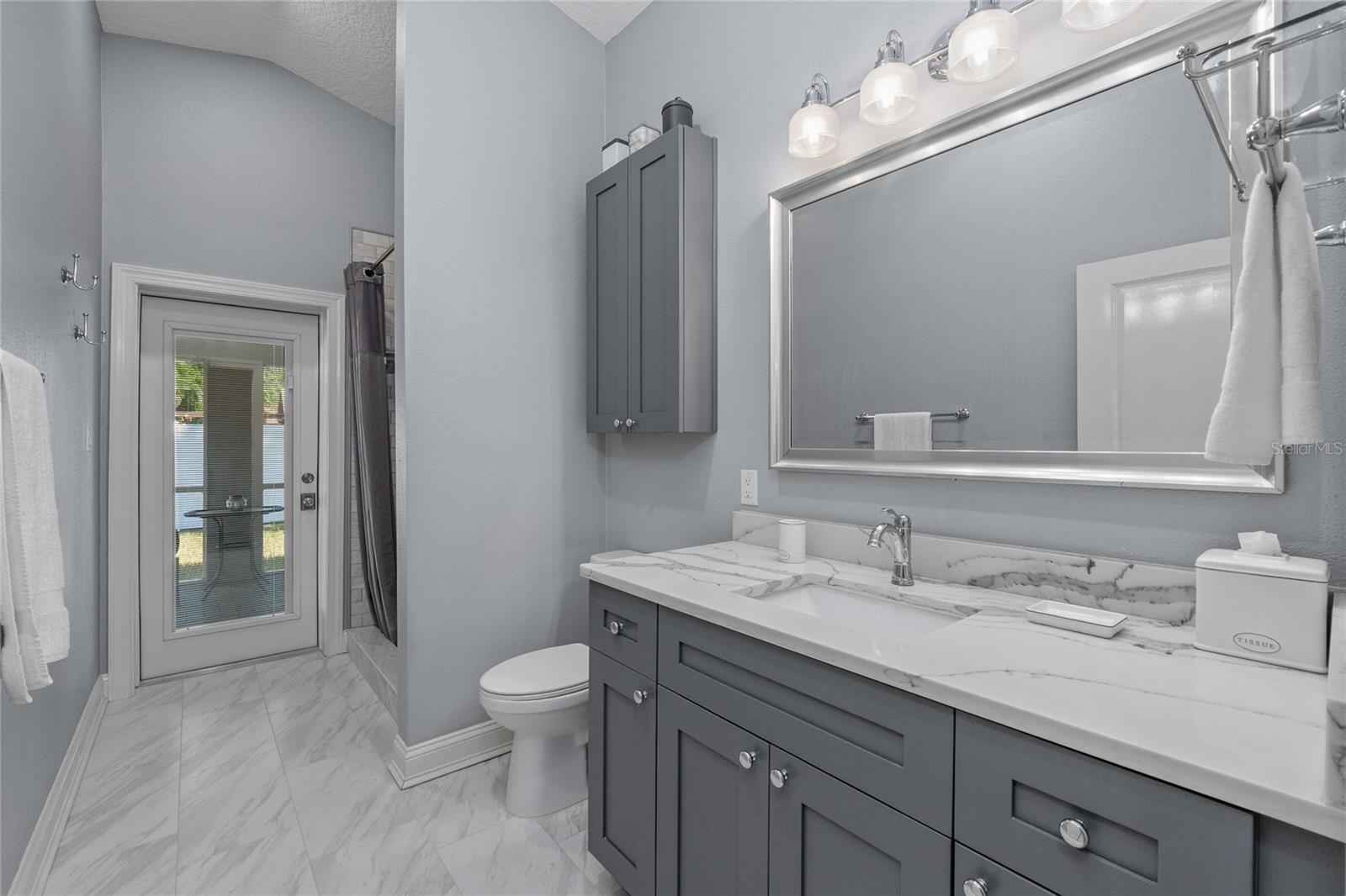 Bathroom has quartz countertops, a large vanity and a large tiled shower