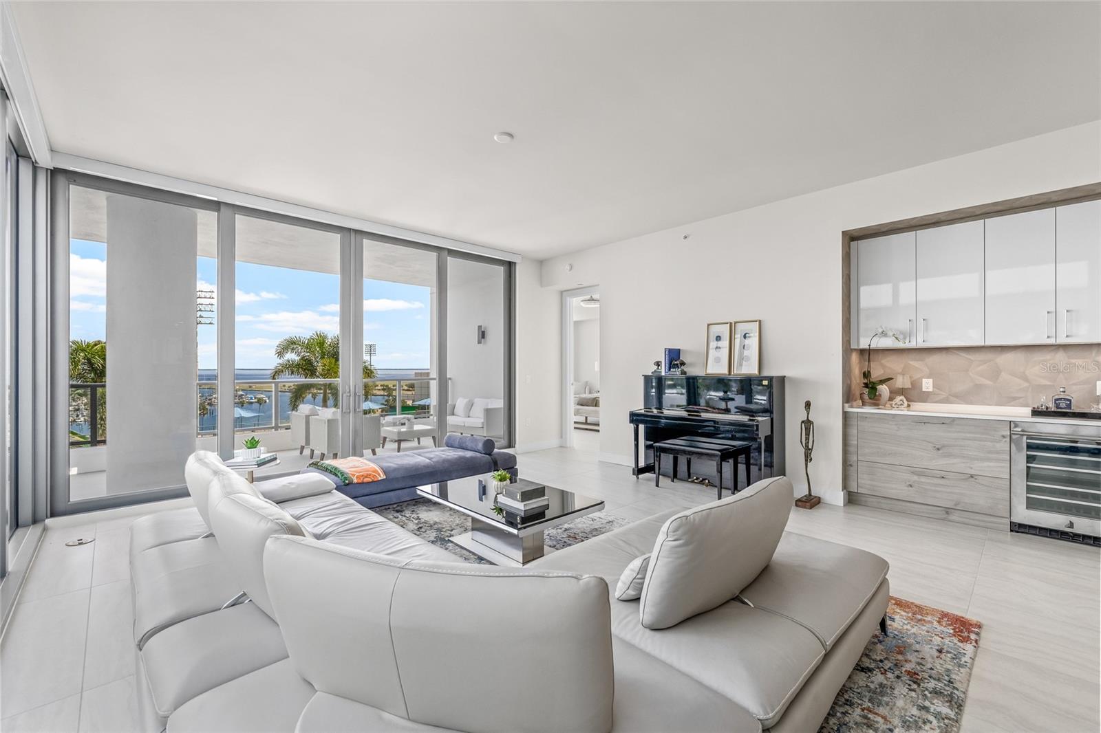 Expansive floor-to-ceiling sliders / windows fill the home with natural light, with the primary bedroom just to the right.