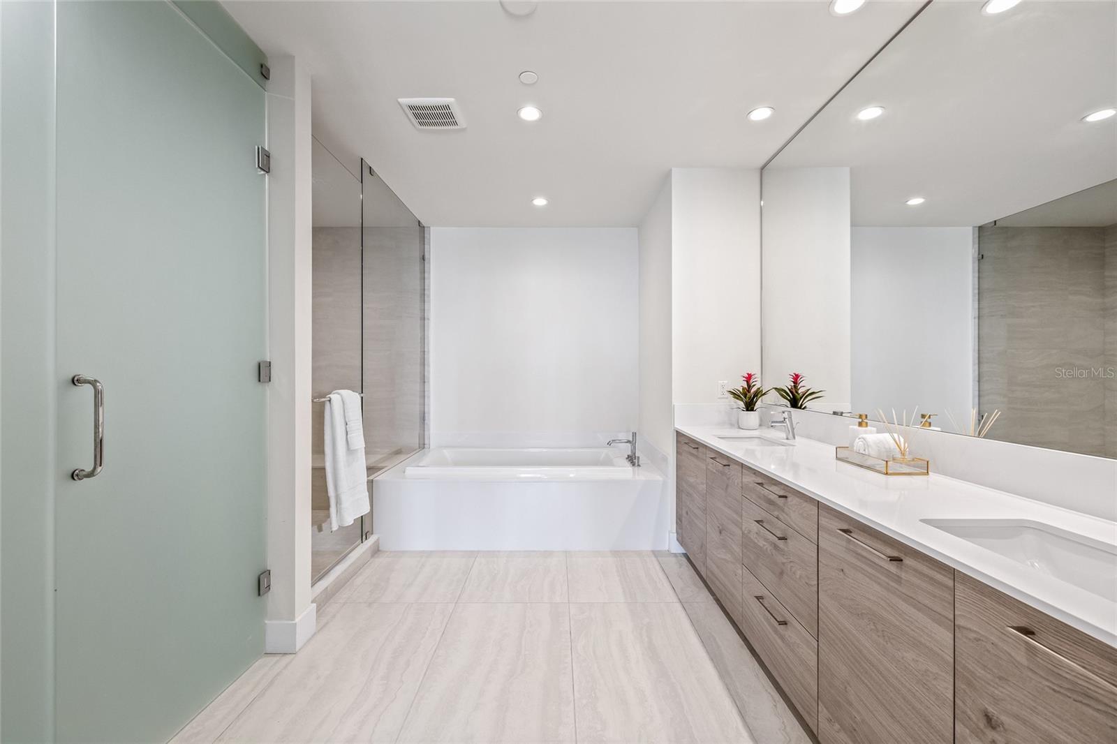 The spa-inspired primary bathroom showcases a dual-sink vanity, a sleek walk-in shower, and a separate soaking tub.