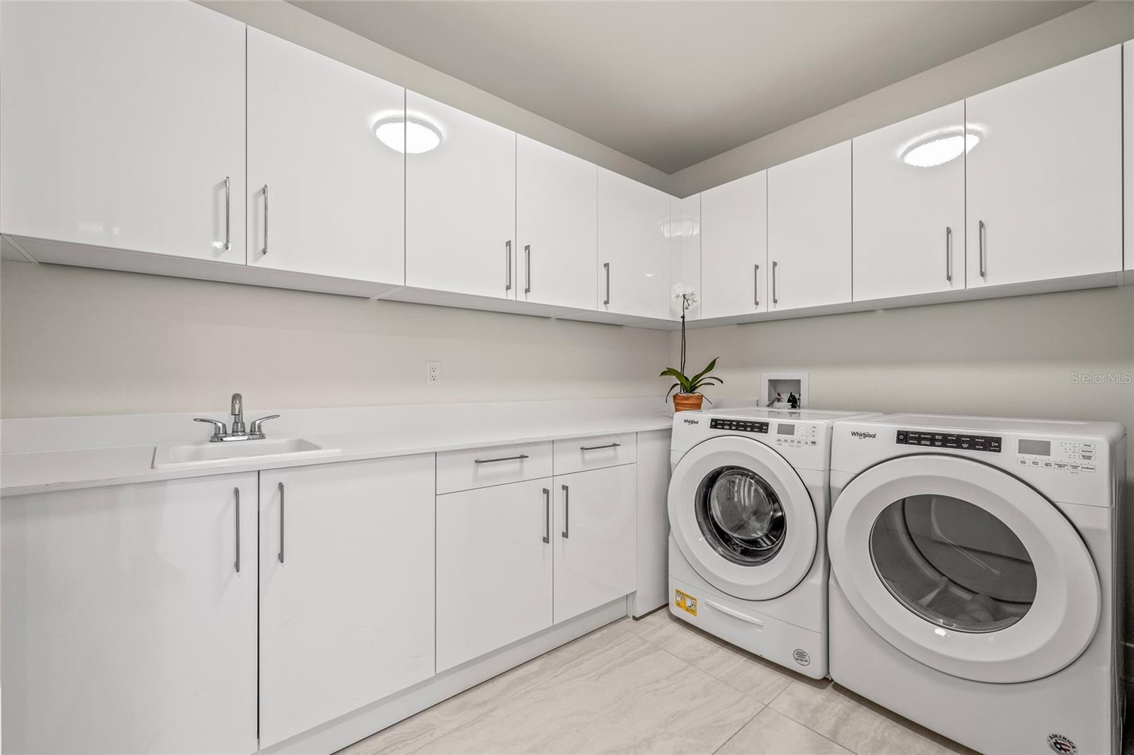 The full-size laundry room offers abundant cabinet storage, generous folding space, and comes equipped with Whirlpool washer and dryer.