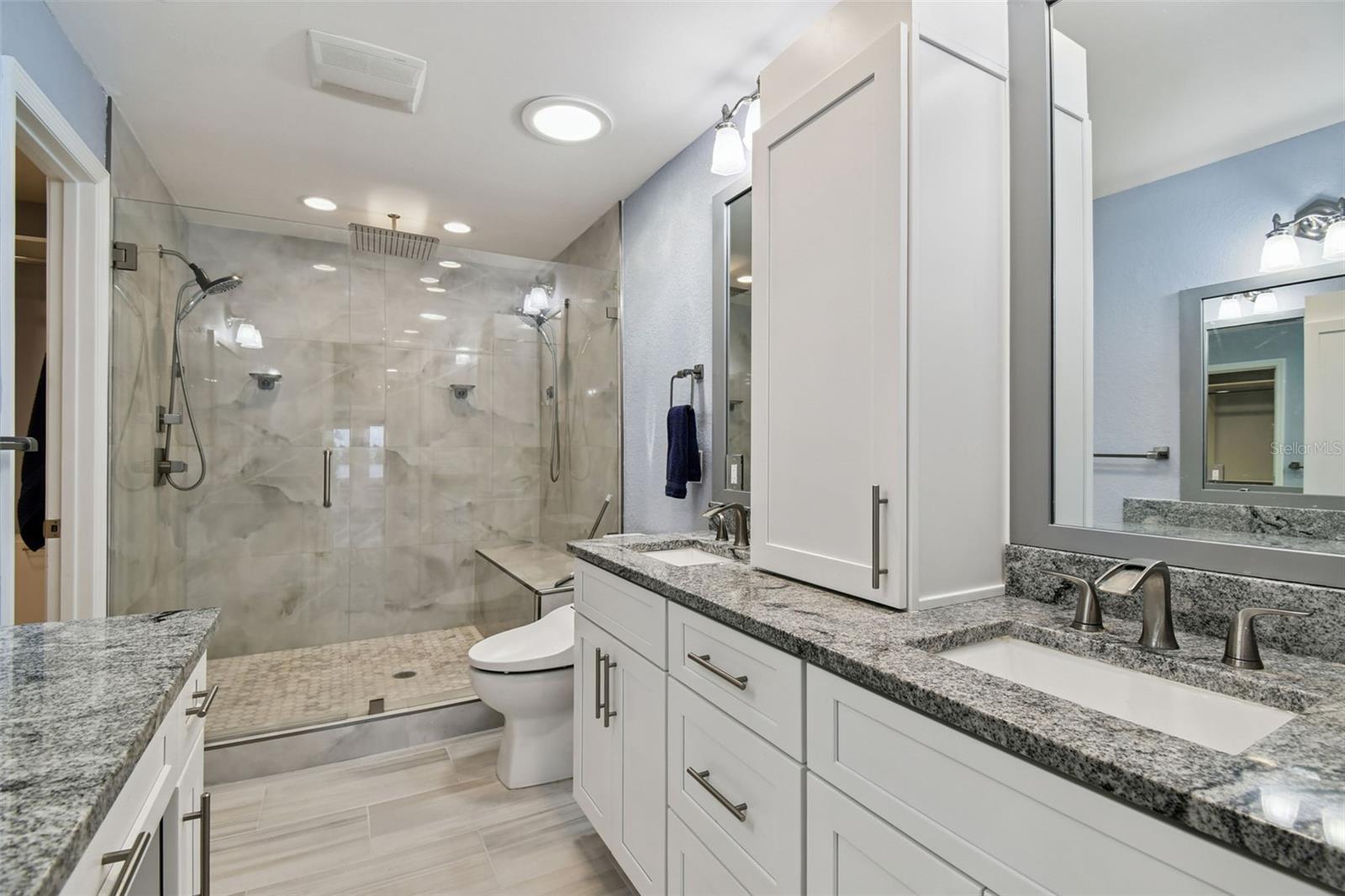 Primary bathroom with double sink vanities and over-sized shower stall.