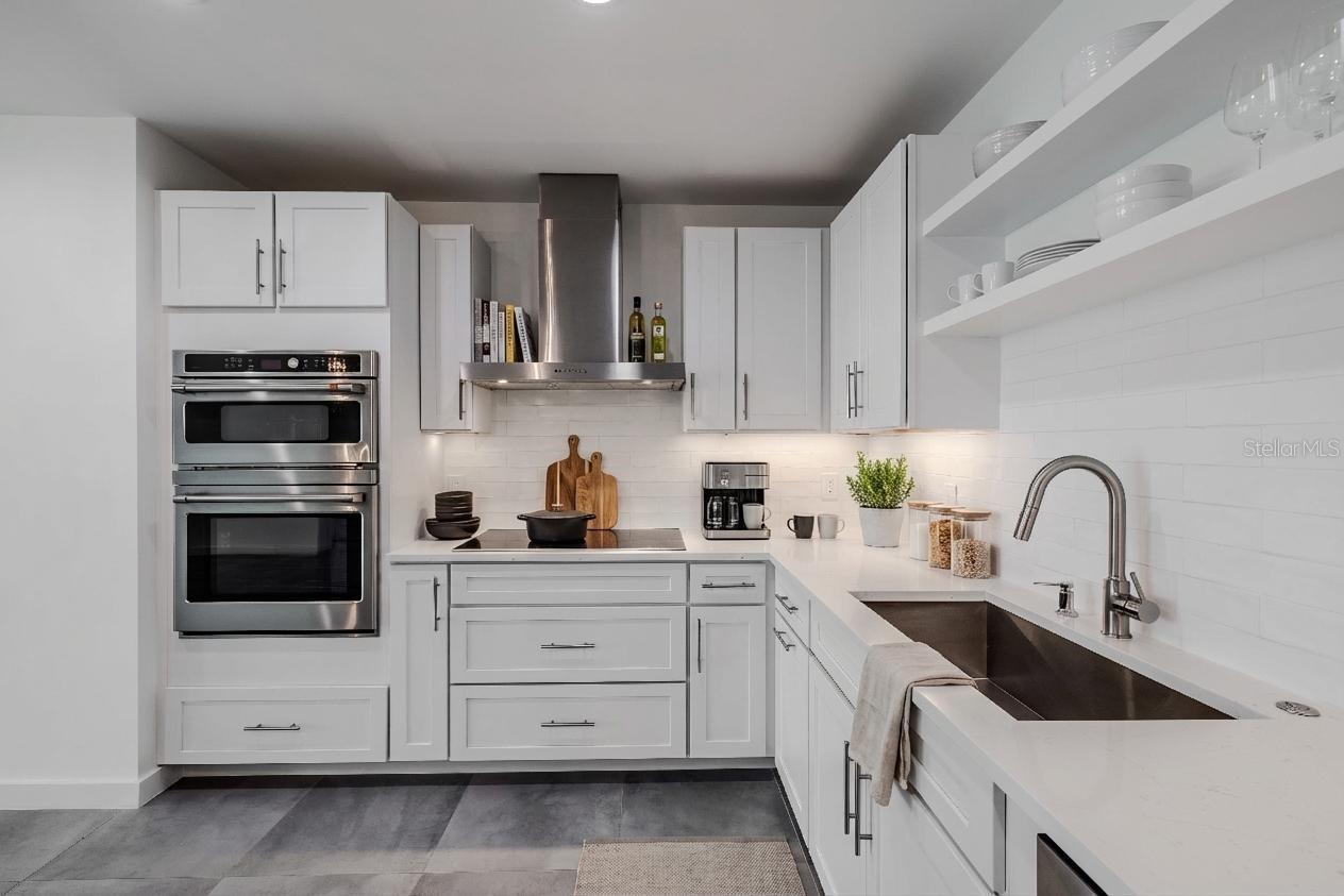 High-end stainless-steel appliances include a French door refrigerator, dishwasher, double wall ovens, and a vent hood. Large  tile floors and under-cabinet lighting complete this bright, sophisticated culinary space.