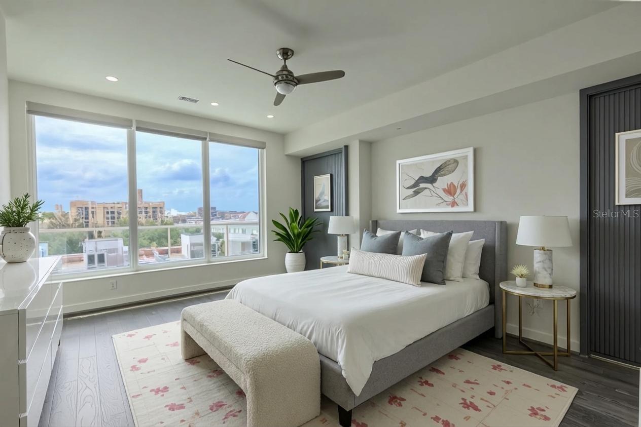 2nd Bedroom: This light-filled bedroom offers sweeping views through a wall of floor-to-ceiling windows that capture both the cityscape and the Intracoastal beyond. Rich hardwood floors and a modern ceiling fan lend a contemporary yet warm feel to the space.