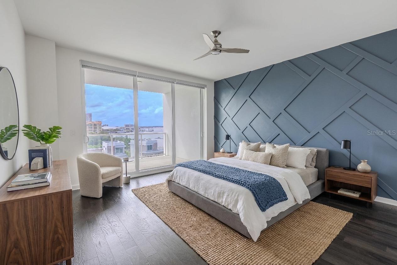 The primary bedroom features a striking custom accent wall that adds architectural depth and modern sophistication. Painted in a rich slate blue, the wall showcases a geometric grid pattern of raised molding, creating a dramatic focal point that complements the room’s sleek aesthetic. The textured design plays beautifully against the dark hardwood floors and natural light, offering the perfect balance of contemporary style and visual interest.