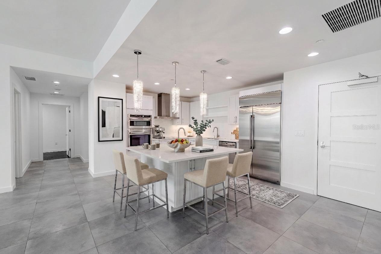 This show stopping modern kitchen is the centerpiece of the home, designed for both style and functionality. A sleek quartz island with storage and sink and bar seating anchors the open concept layout, framed by elegant crystal pendant lighting that adds a touch of glamour.
