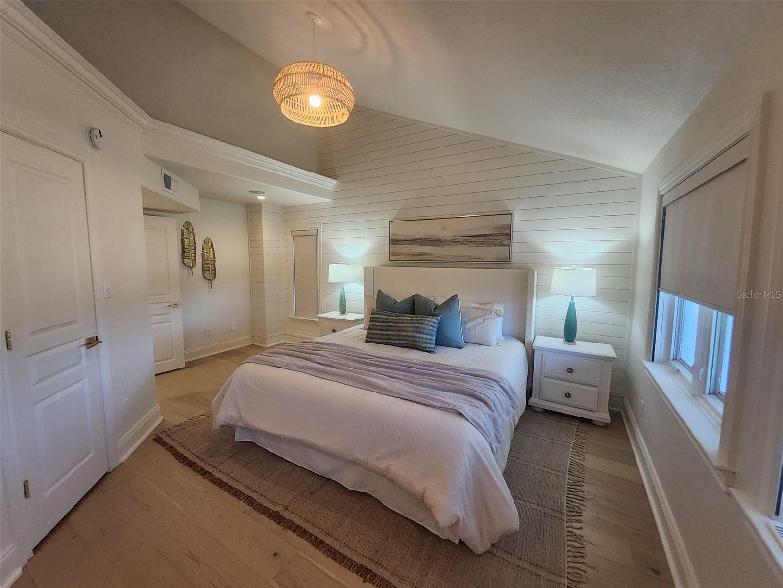 Primary bedroom with shiplap wall and vaulted ceiling