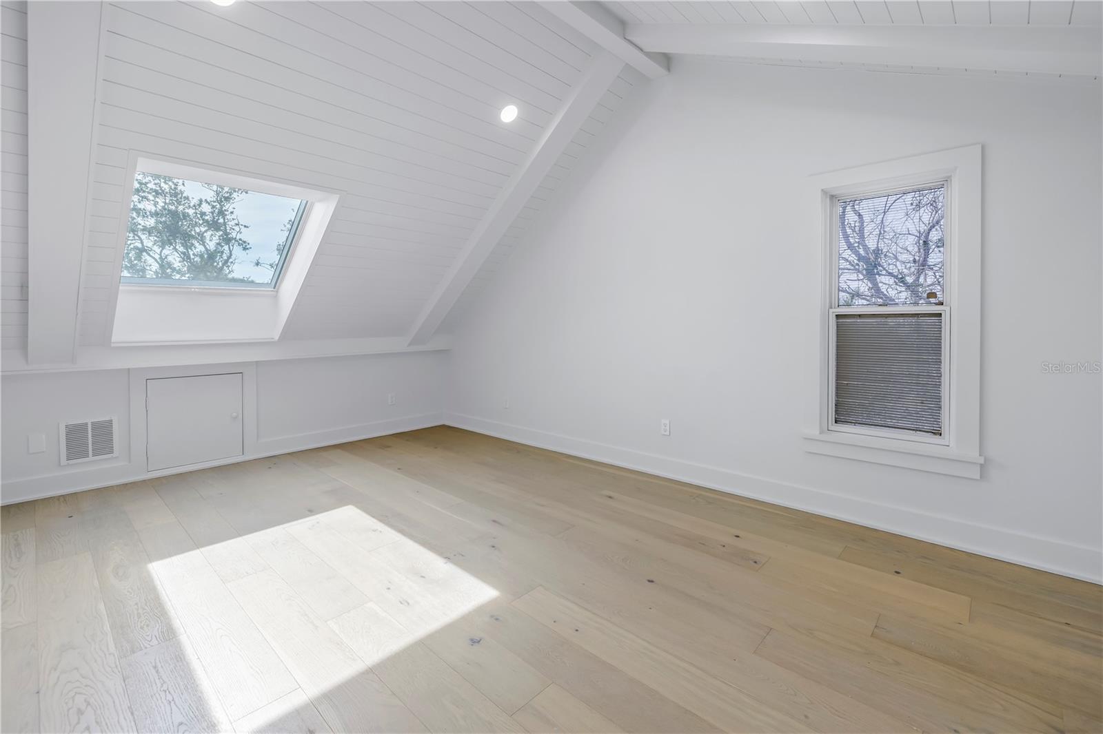 Bedroom  on upper level with new skylight with motorized shade, shiplap ceiling with faux beams and recessed lighting