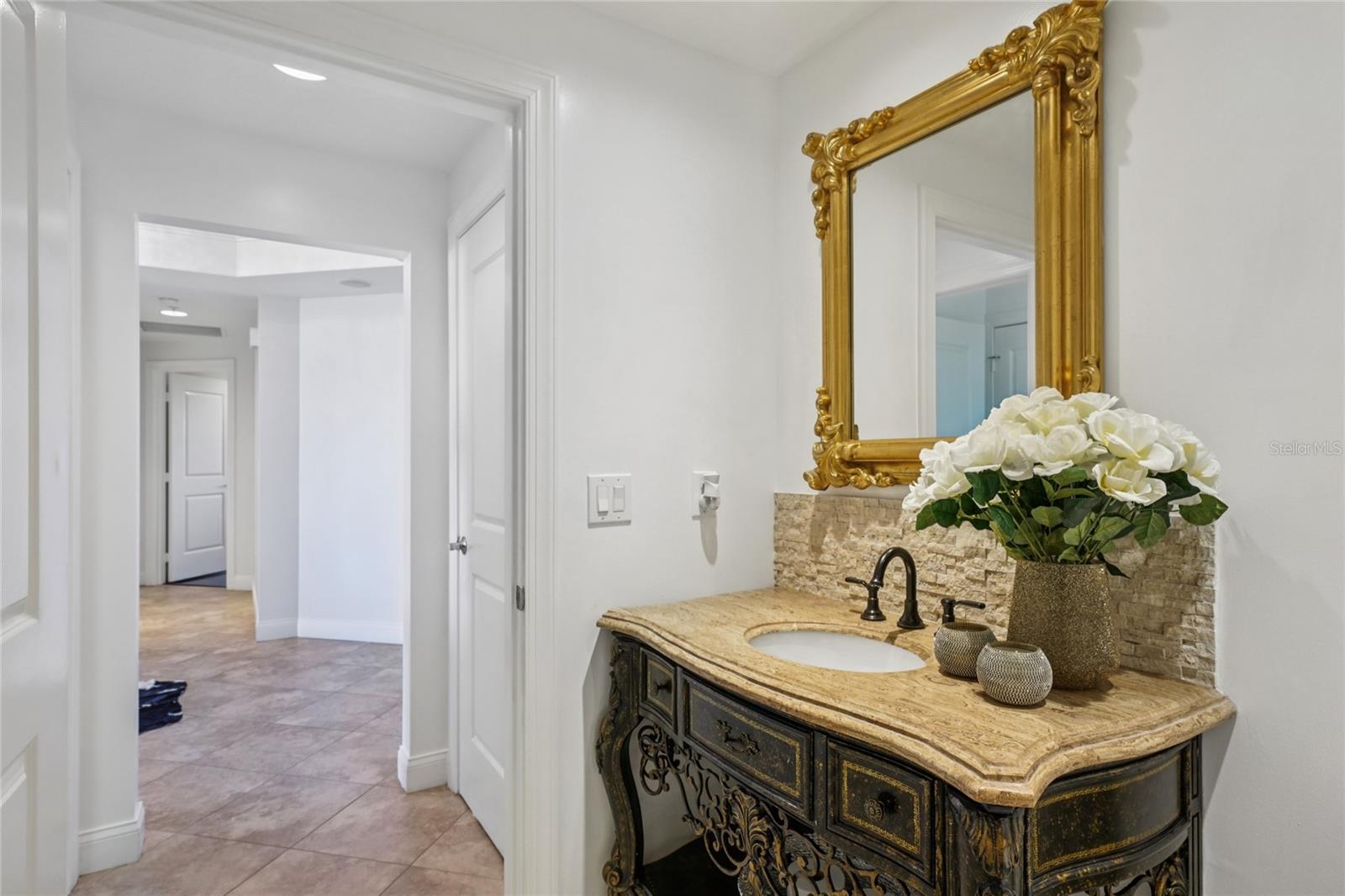 Half bathroom featuring designer vanity,gold framed mirror perfect for guests