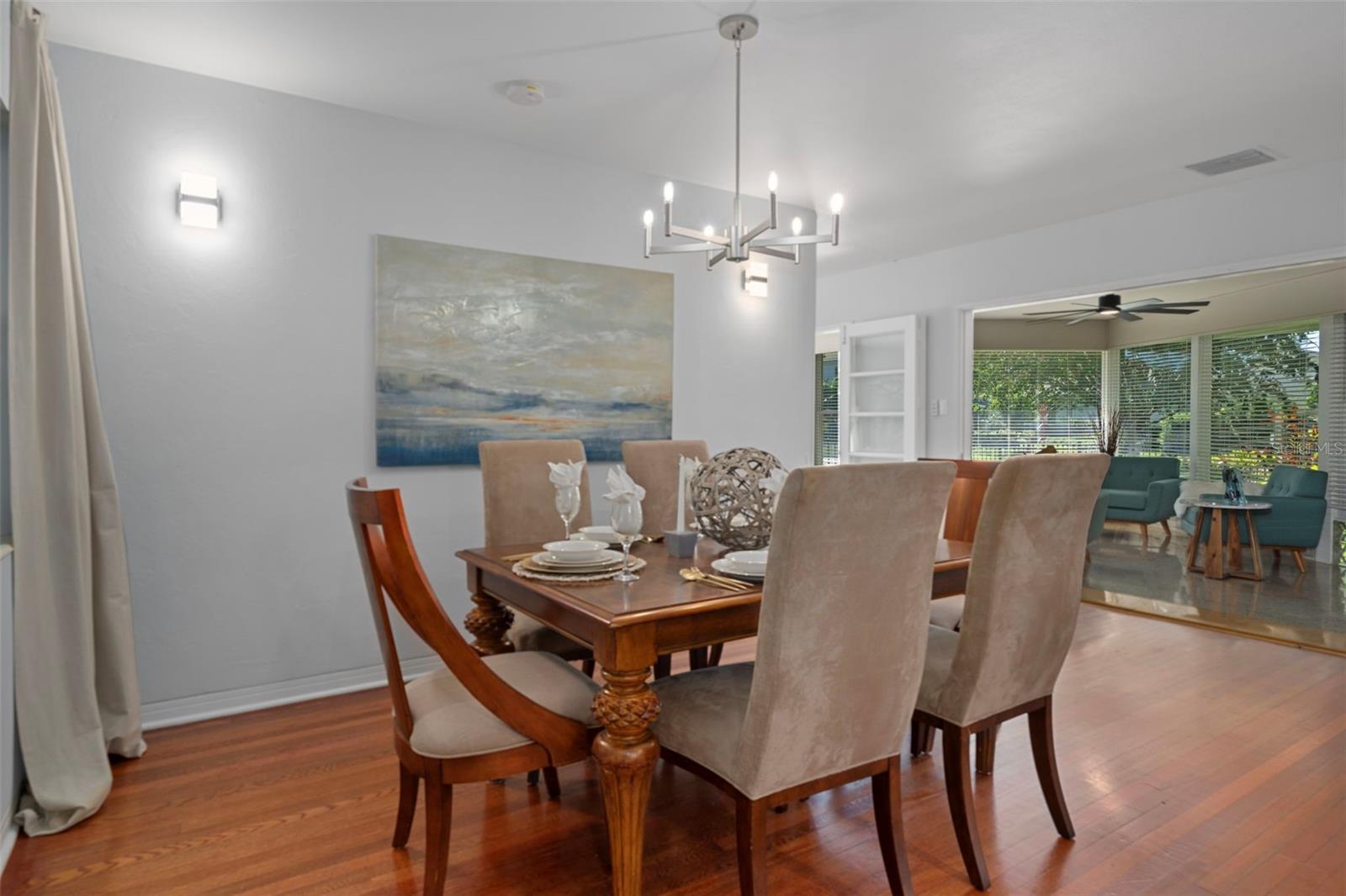The dining room with hardwood floors and seamless flow into the sunroom and the kitchen.