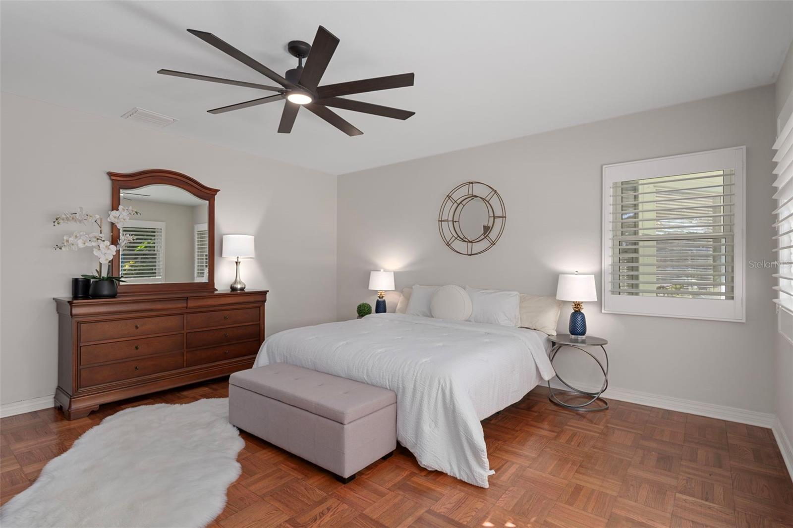 Spacious primary bedroom with plantation shutters and a ceiling fan.