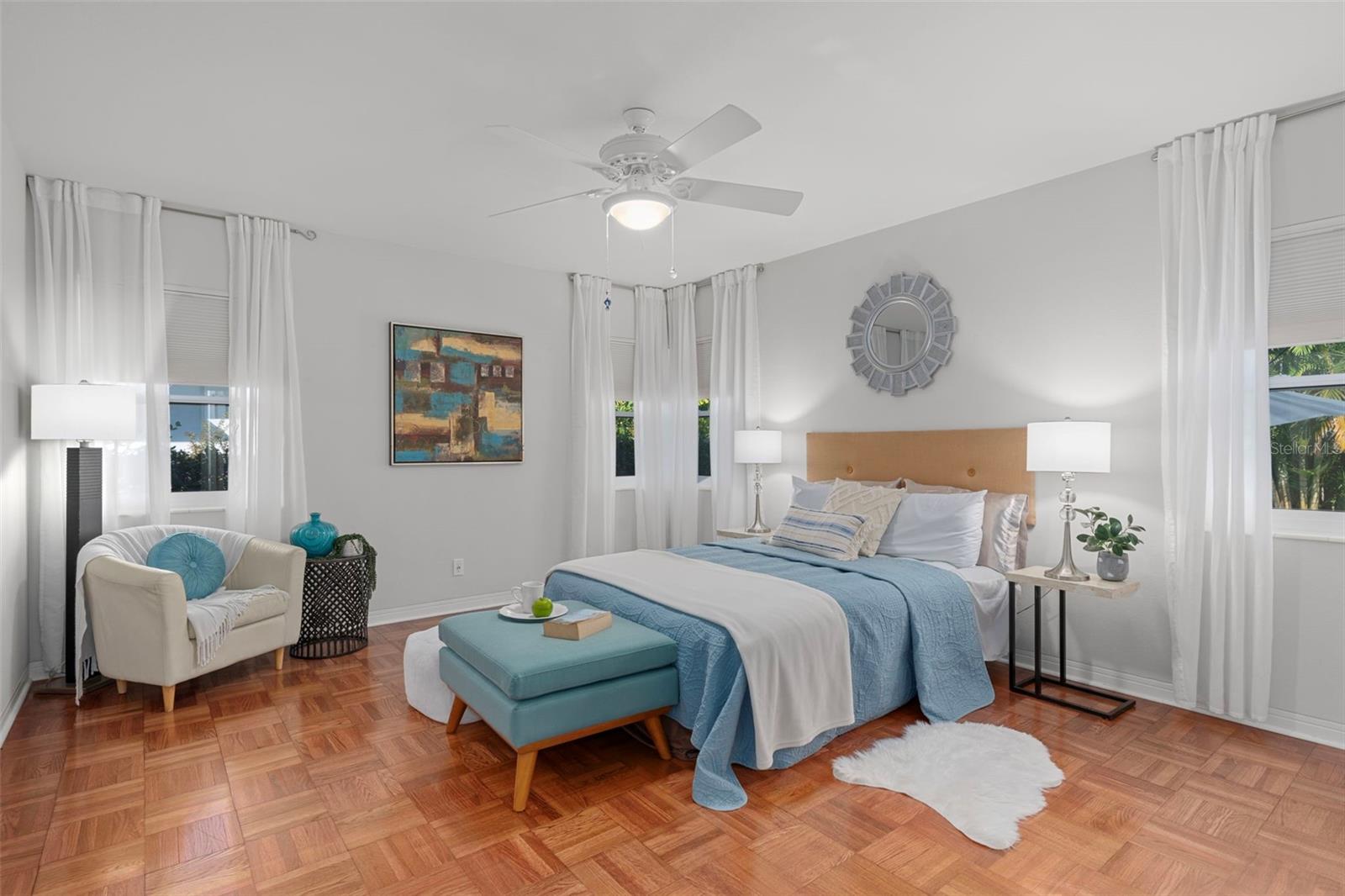 Spacious second bedroom with warm natural light and beautiful parquet flooring.