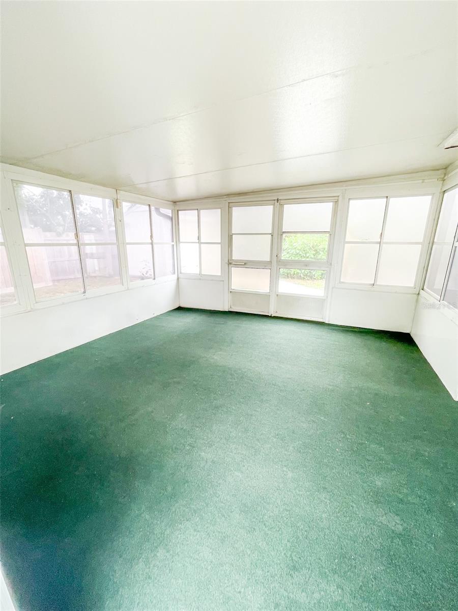 Large screened in patio features doors that open on both sides of the yard.