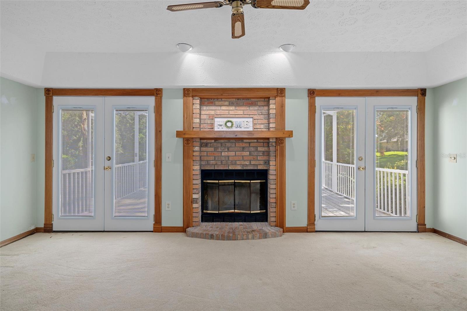 Family Room with Wood Burning Fireplace and Double French Doors to Lanai