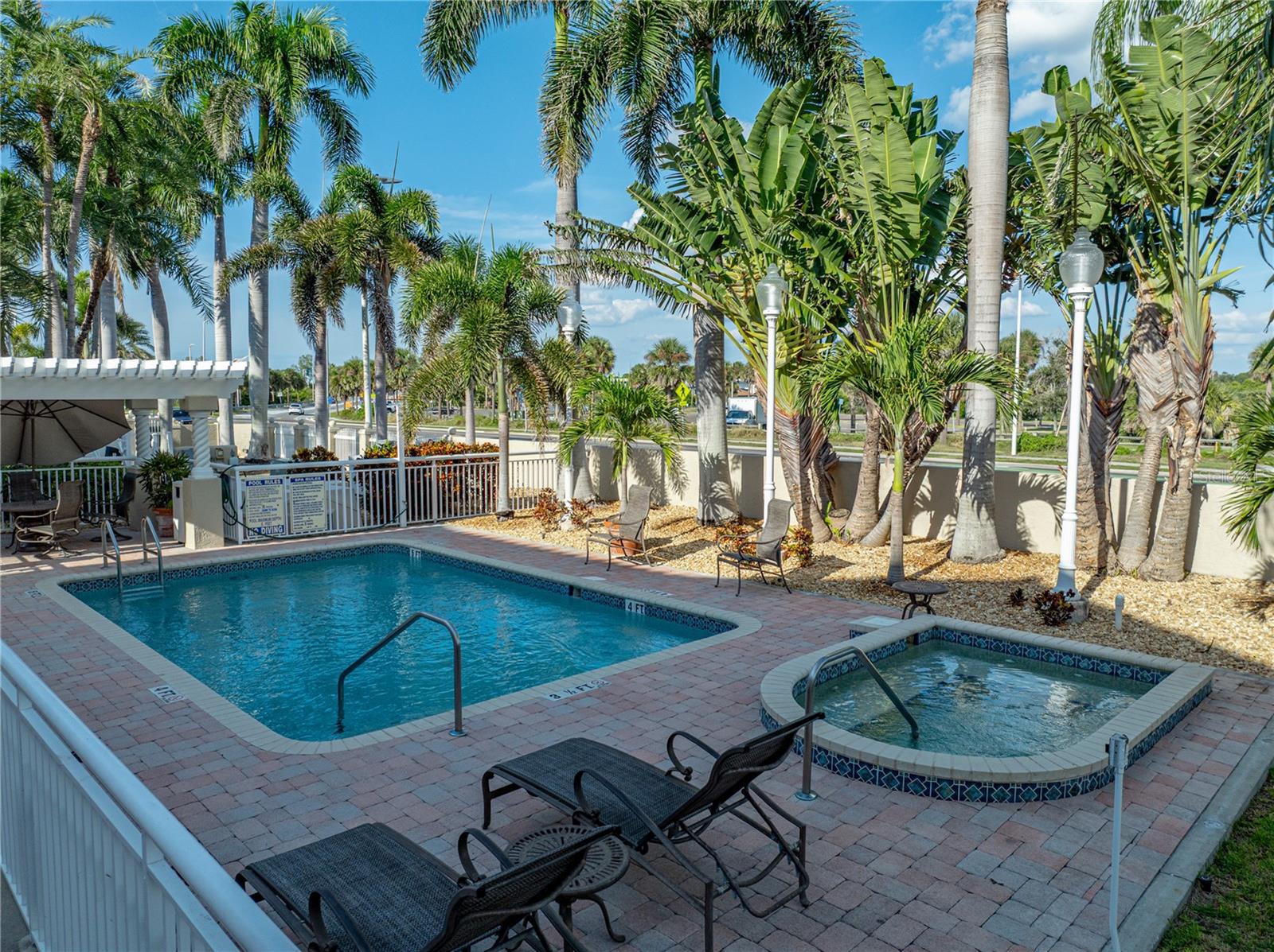 Fenced in pool area and hot tub, well-lit at night