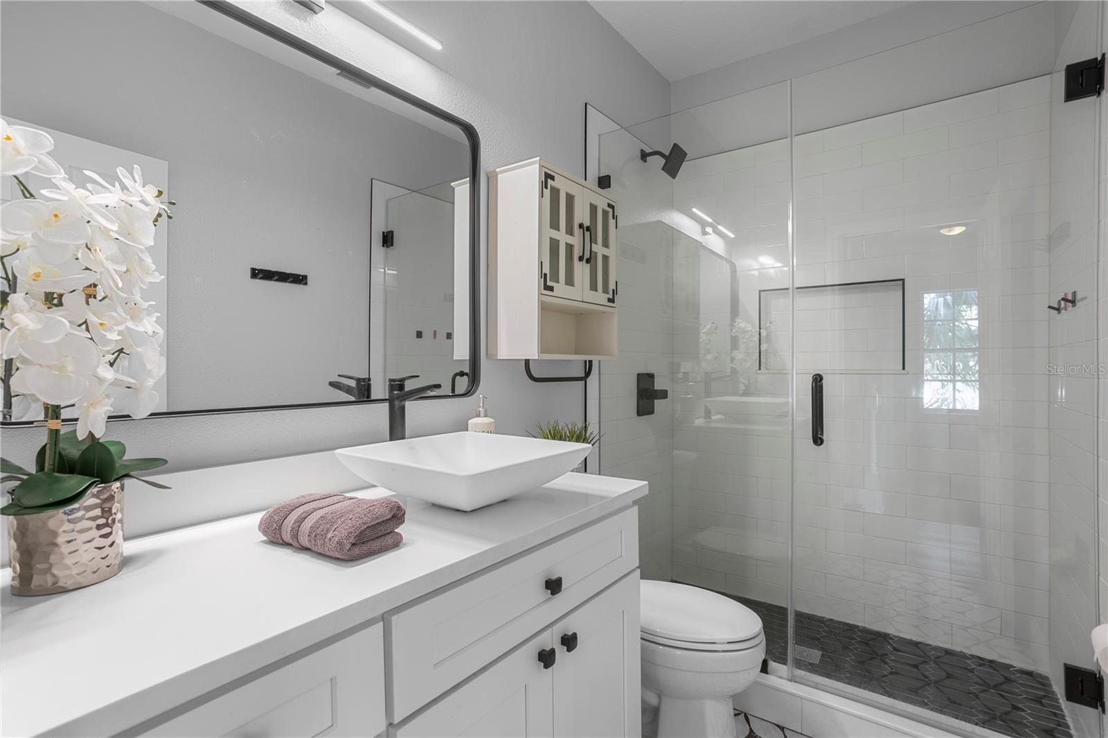 Beautifully updated bathroom showcasing thoughtful in-shower storage and a calming design.