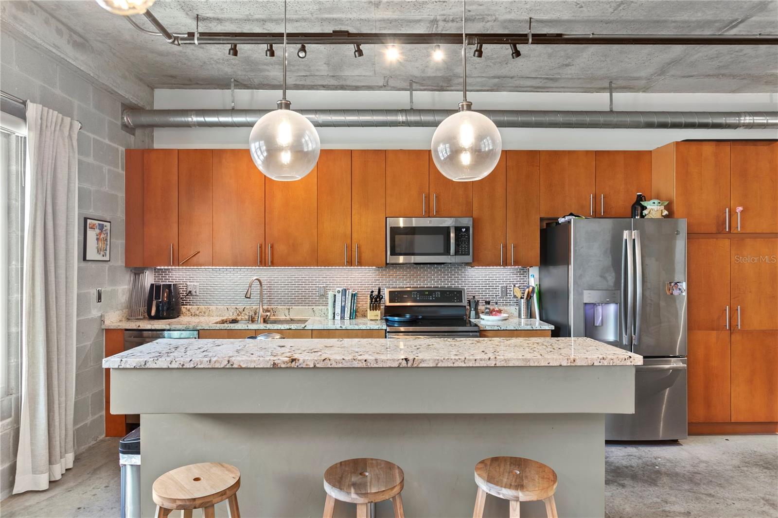 Modern kitchen with sleek cabinetry, granite countertops, pantry and stainless appliances.