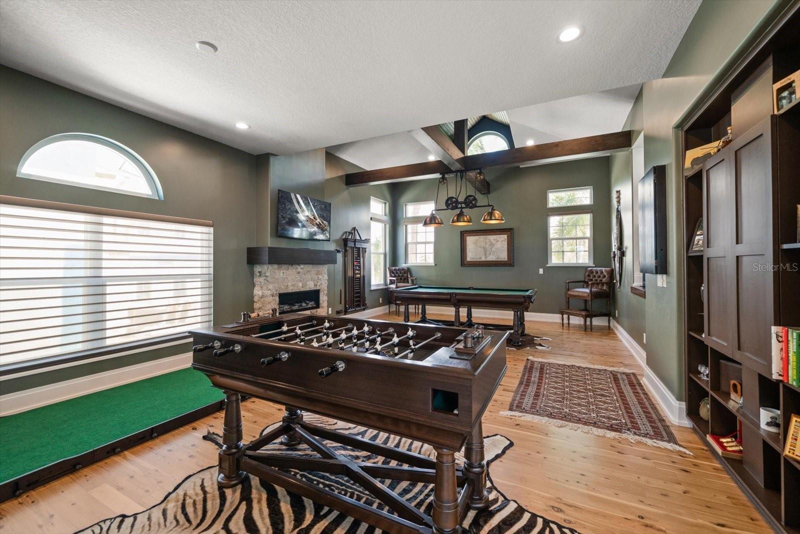 The game room has a gas fireplace and unique Torque Linear Chandelier