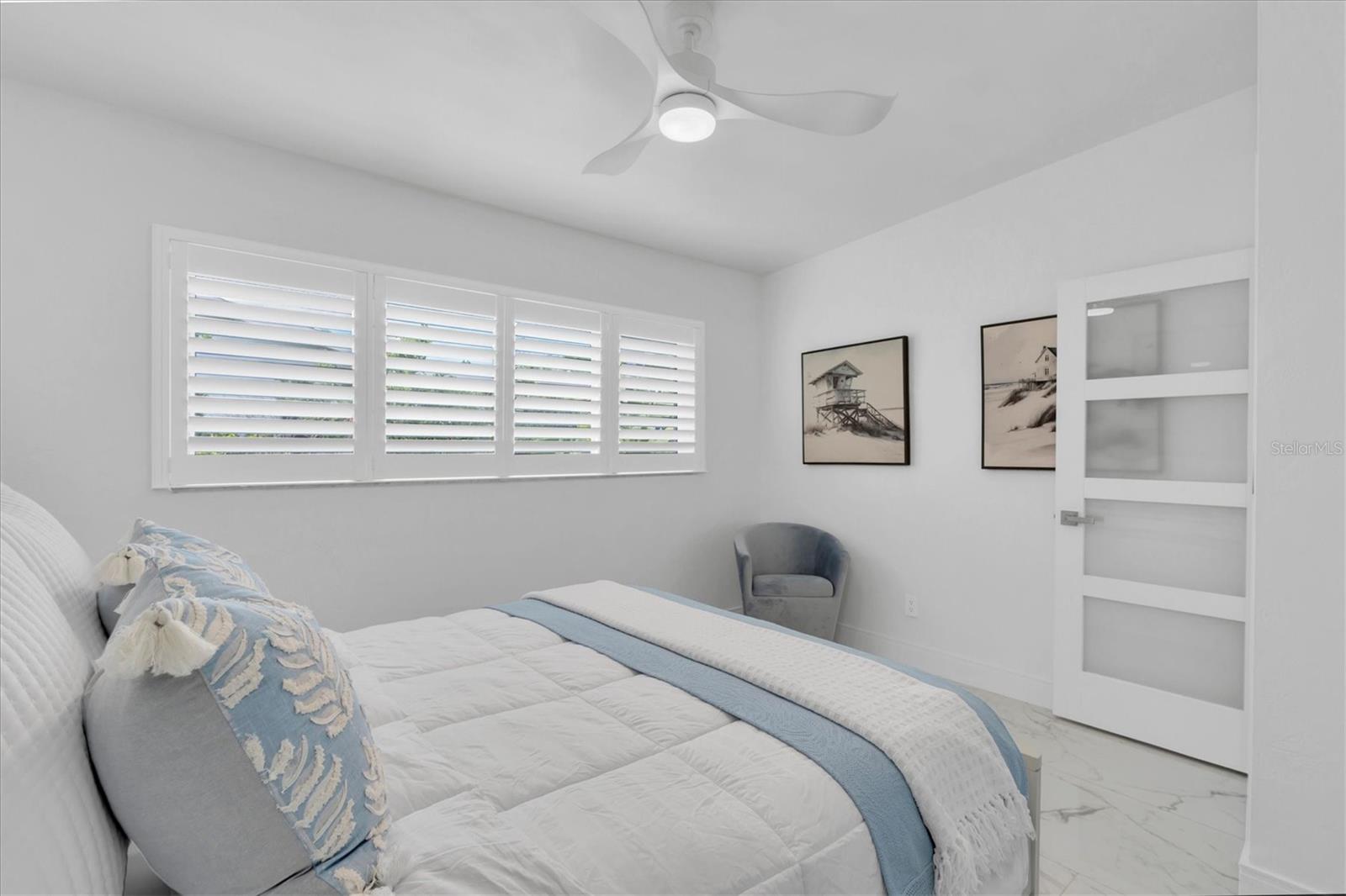 The second bedroom features plantation shutters, lovely tiled flooring with a coastal flair.