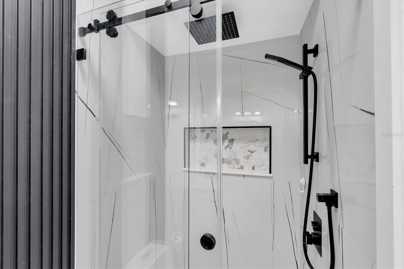 Designer shower with glass doors, built-in niche, and a luxurious waterfall showerhead with handheld sprayer.  You will definetly enjoy taking a shower!