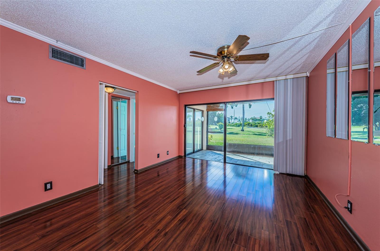 Main living area with laminate flooring and sliding doors leading to private screened patio