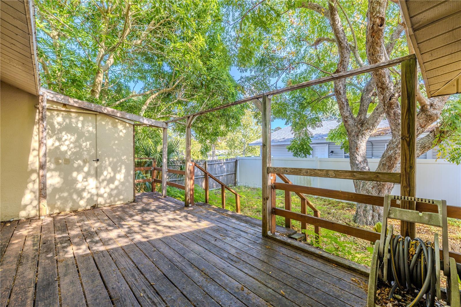 Stepping out from the screened-in porch, to your left you will find a spacious wooden deck—ideal for outdoor dining, grilling, or relaxing under the shade of mature trees. To the left, a dedicated storage room offers convenient space for tools, lawn equipment, or seasonal items. The fenced-in backyard provides privacy and a secure area for pets or play, creating a versatile outdoor retreat perfect for everyday enjoyment.
