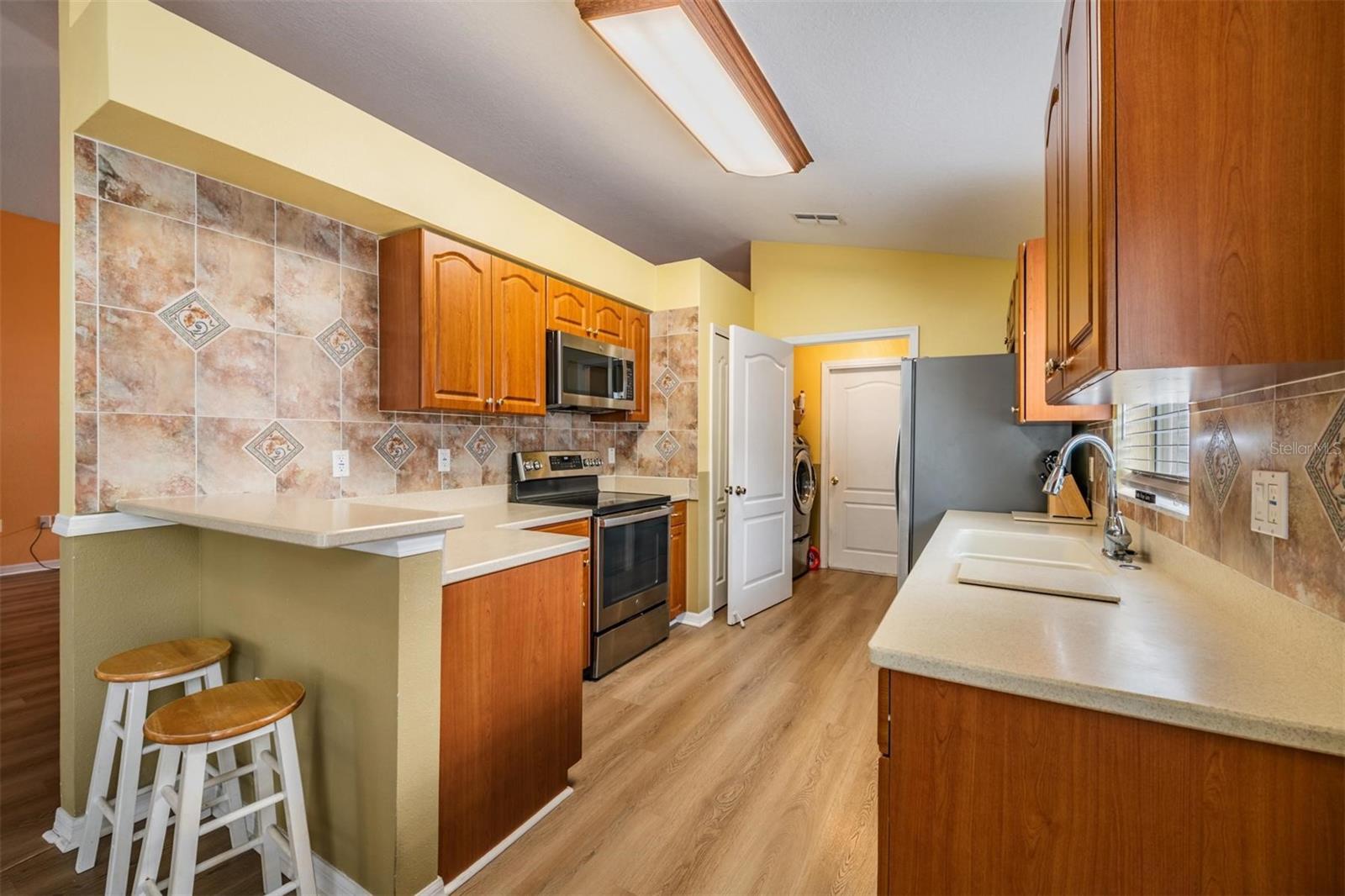 Bright kitchen with bar and laundry room which leads into the garage.