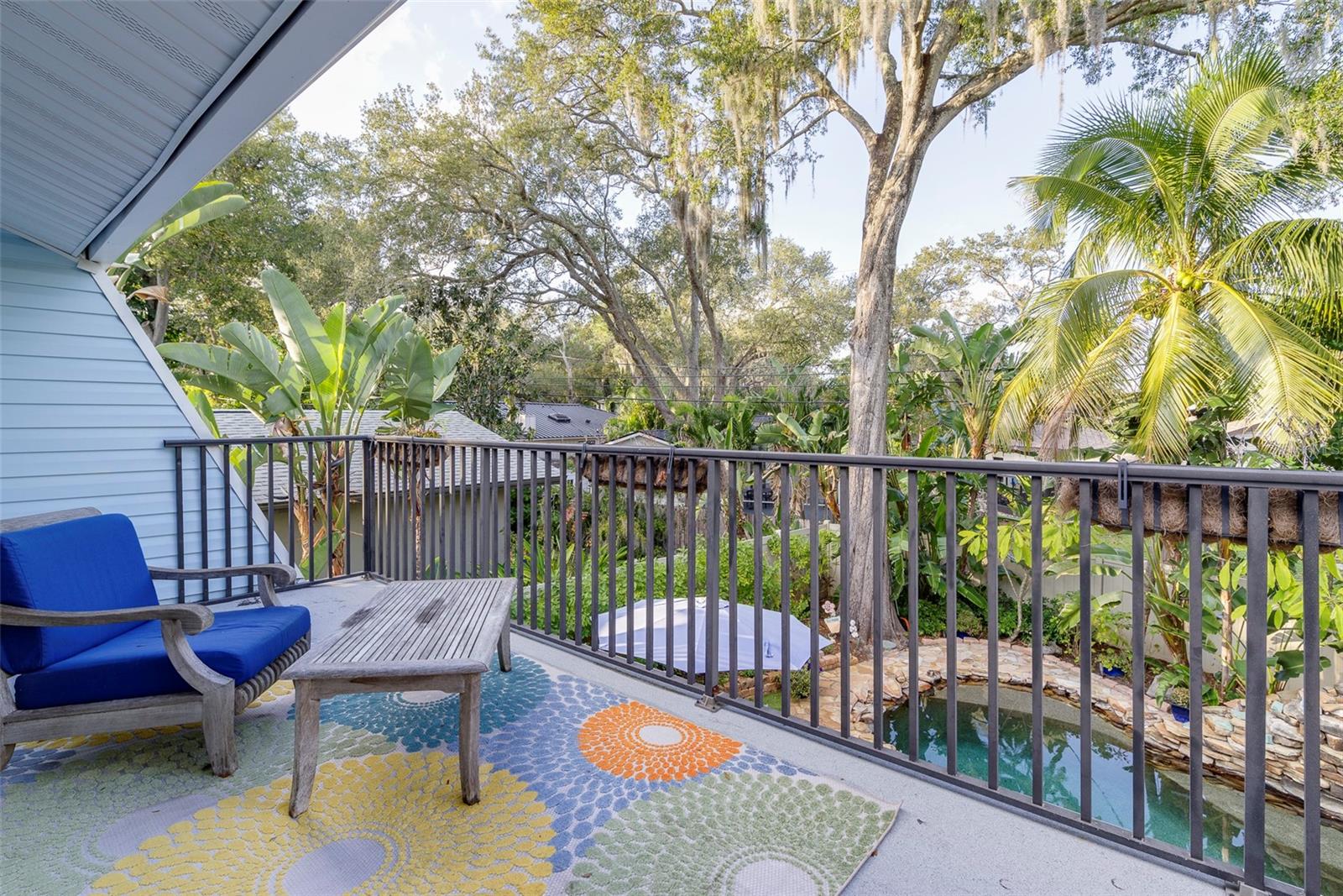 The private balcony off the primary bedroom provides a serene sanctuary overlooking the stunning pool and landscaping.