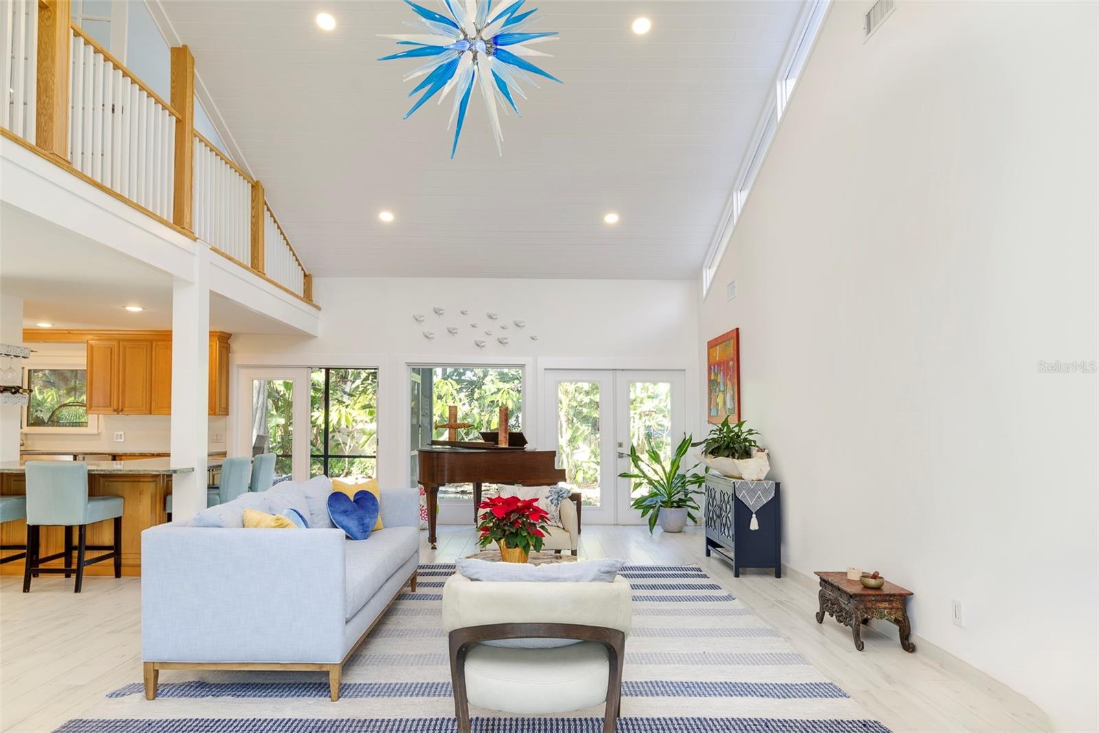 The picture windows and French doors across the back of the home lead your eye to the breeze, lush backyard. The custom lit glass sculpture hanging in the living room was artisan created from Murano, Italy and available for separate purchase.