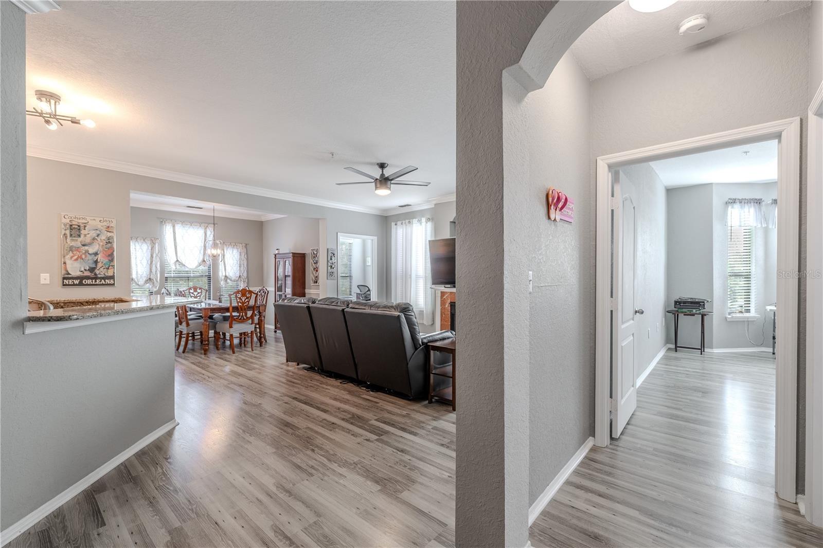 This view highlights the seamless flow from the open living and dining area into the private hallway leading to the bedrooms, showcasing the unit’s airy layout, cohesive flooring, and thoughtful separation of living and sleeping spaces.