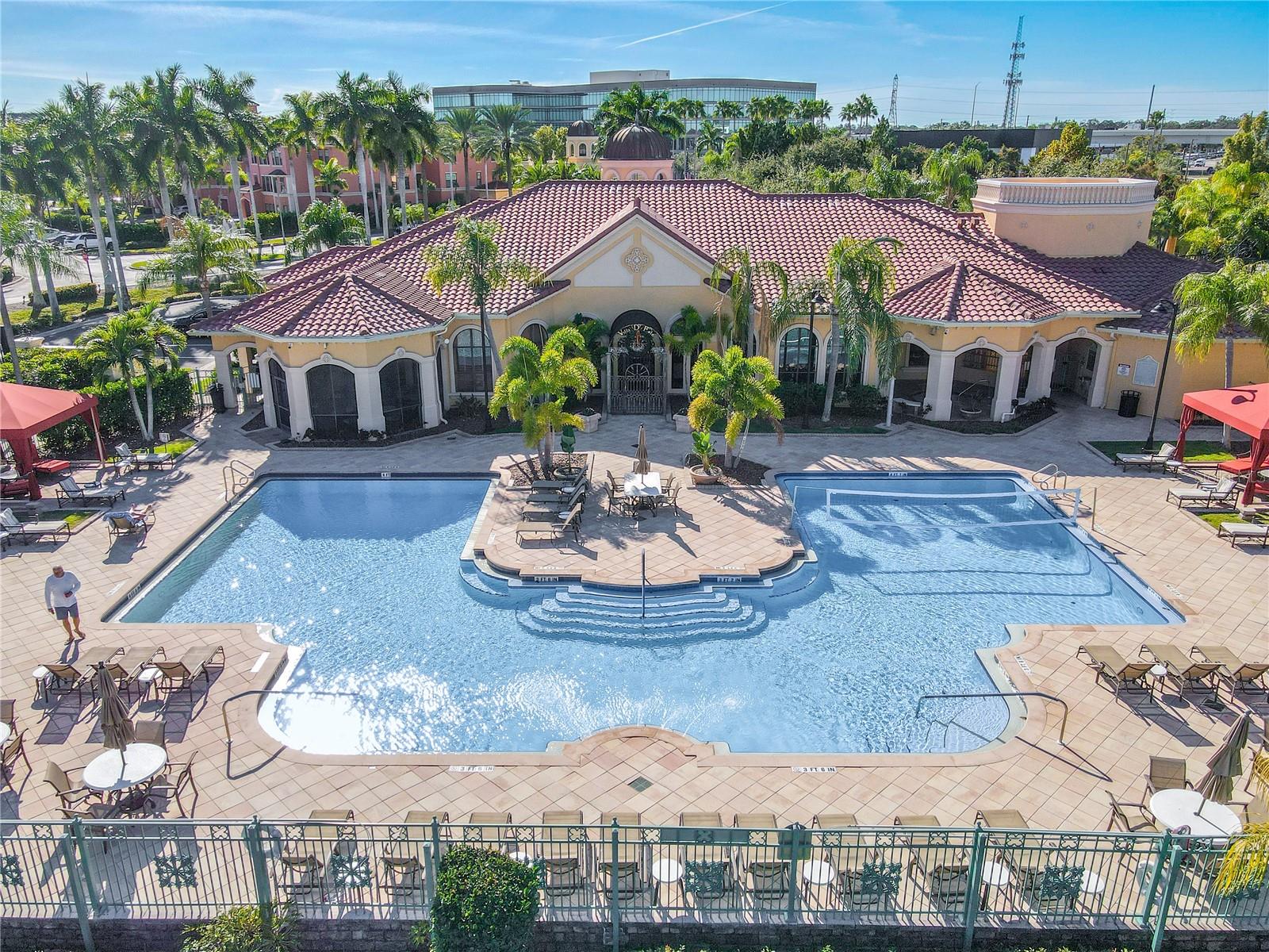 This aerial view further shows the resort-style heated clubhouse pool and spa with a spacious sundeck, lounge seating, and private rentable cabanas—perfect for relaxing, entertaining, and soaking up the Florida sunshine.