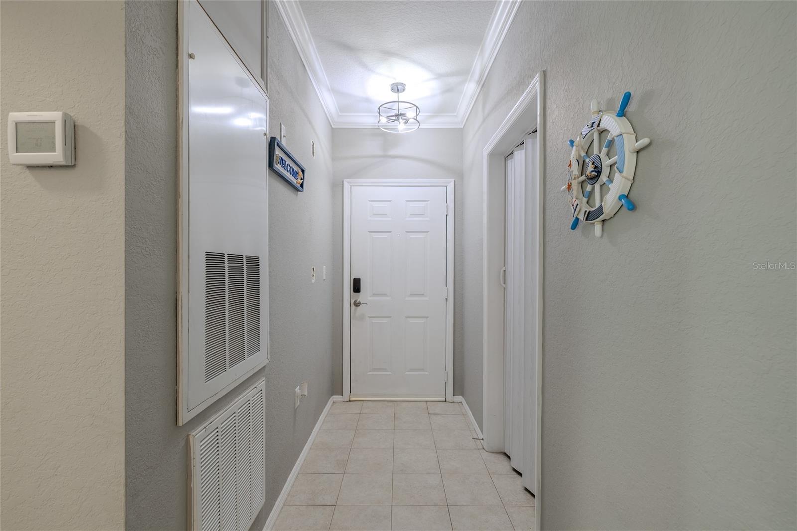 Bright entry foyer with tile flooring and modern lighting, featuring a convenient laundry/utility closet to the left for easy everyday living.