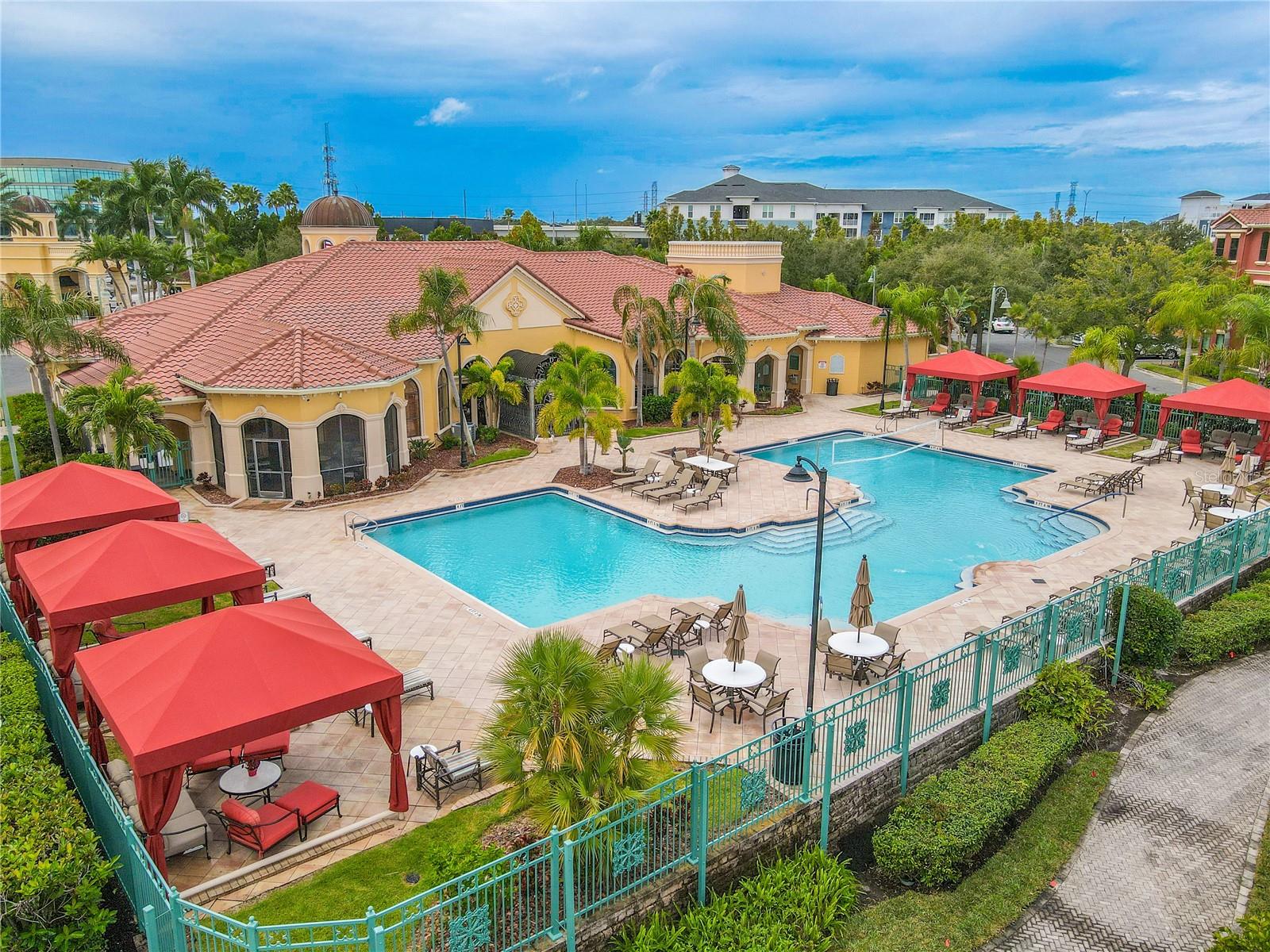 Corner aerial resort-style heated clubhouse pool and spa with a spacious sundeck, lounge seating, and private rentable cabanas—perfect for relaxing, entertaining, and soaking up the Florida sunshine.