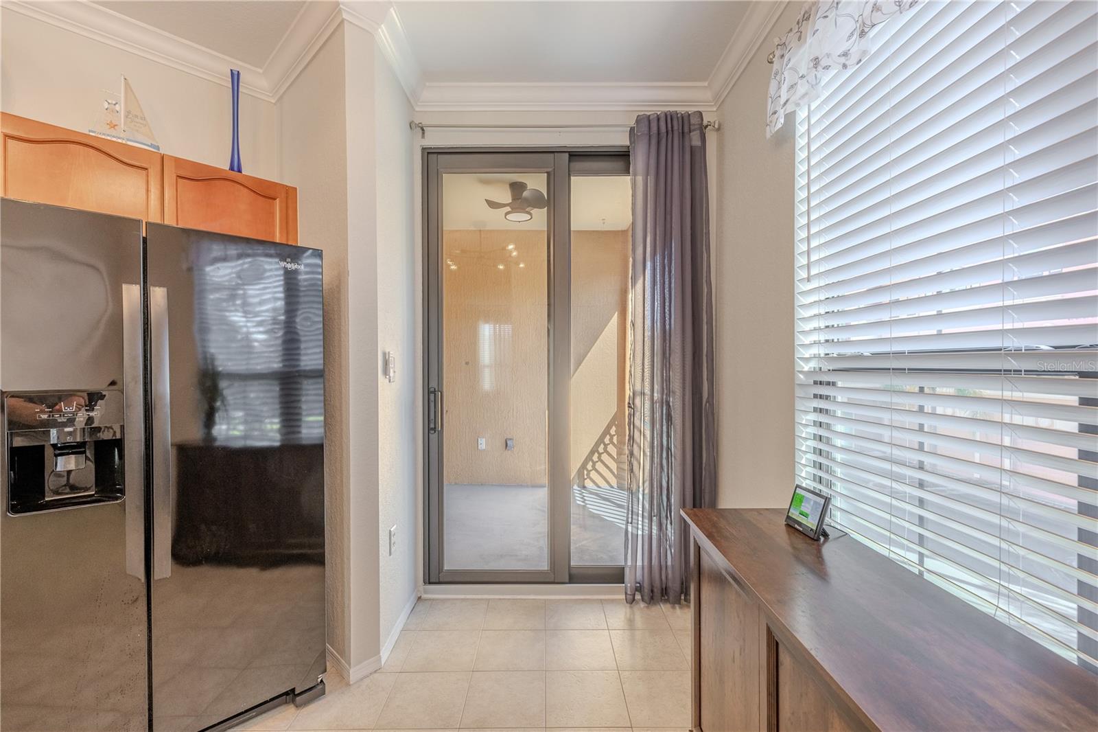 Another view of with natural light that fills this eat-in kitchen area, featuring a large window, tile flooring, modern lighting, and sliding glass doors that open to the private balcony for easy indoor–outdoor living.