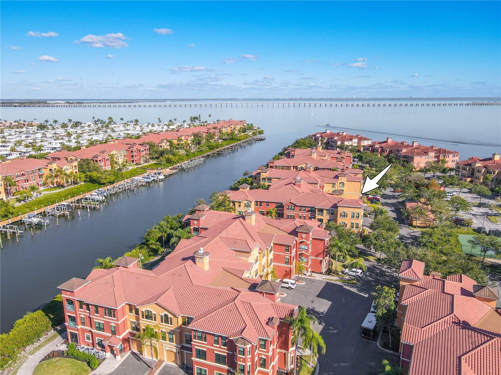 Another elevated aerial view highlights the Mediterranean-style architecture of the Grand Bellagio community, showcasing tile-roofed buildings, palm-lined grounds, and the desirable corner placement of this residence within a beautifully maintained setting.