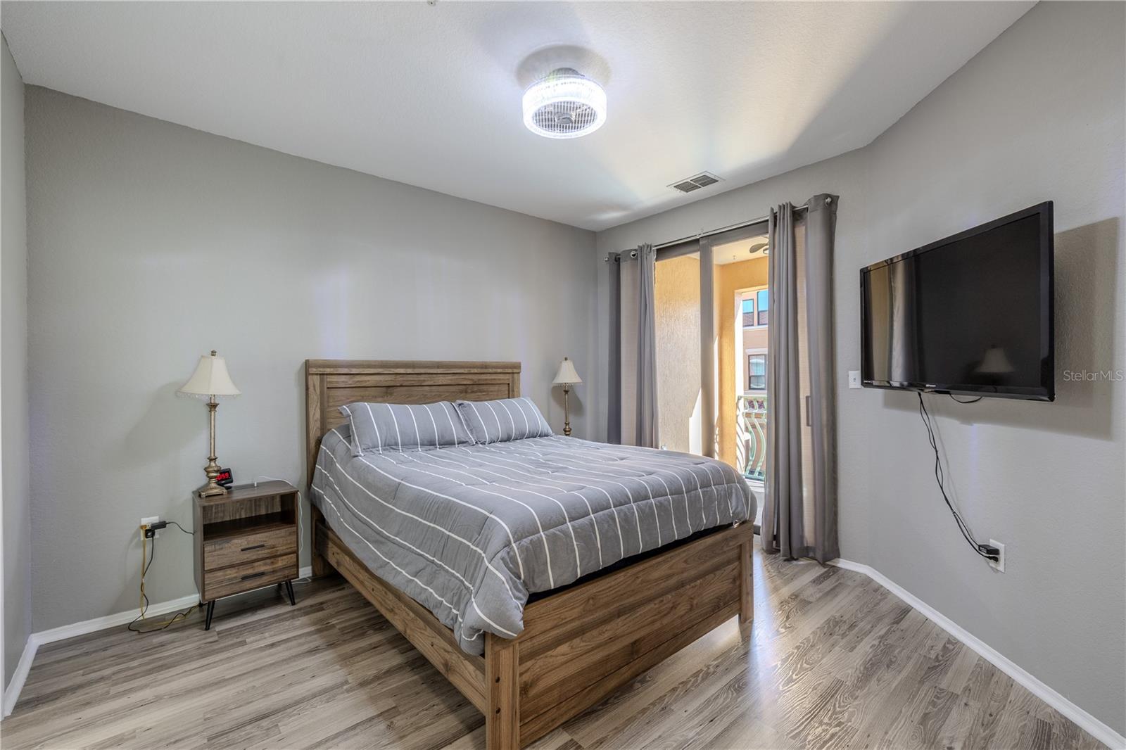Primary bedroom retreat featuring sliding glass doors to the private balcony, soft neutral tones, modern lighting, and easy access to the main living area, creating a bright and comfortable space to unwind.