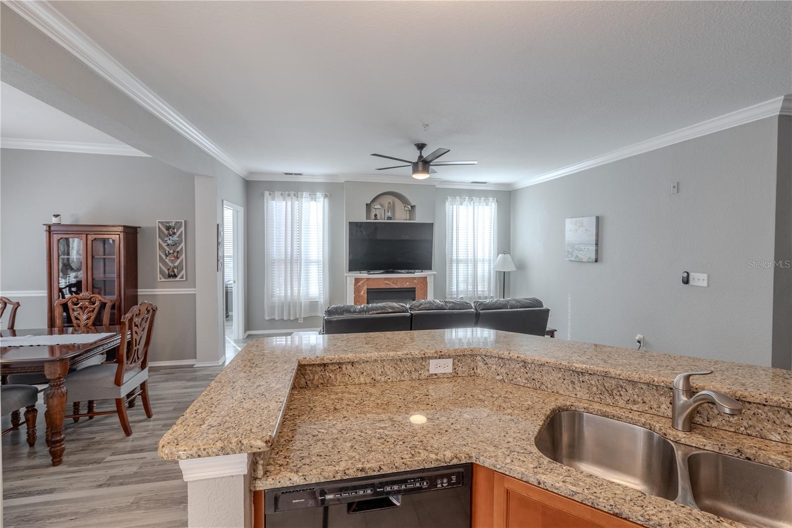 This view highlights the spacious living area with modern ceiling fan, neutral tones, and seamless sight lines into the kitchen, emphasizing the open-concept layout ideal for everyday living and entertaining.