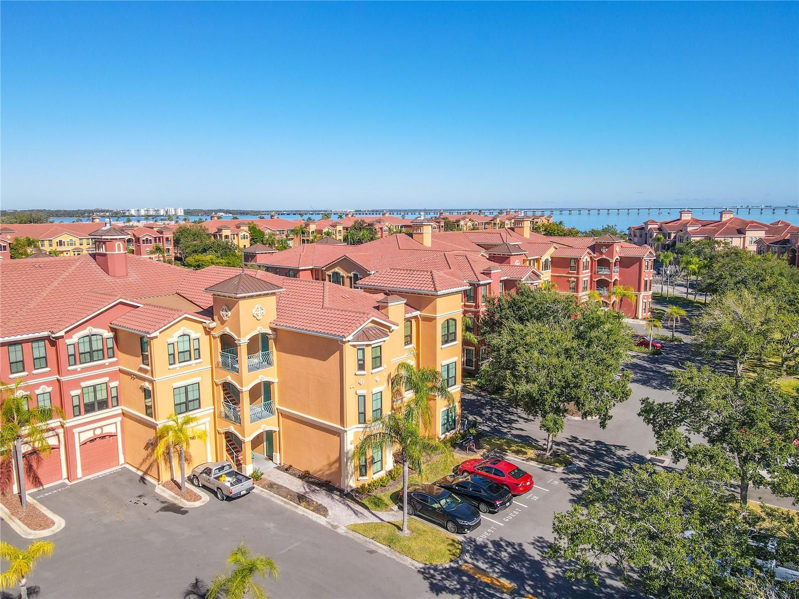 This aerial view highlights the sun-drenched Mediterranean elegance rising above palm-lined grounds, welcoming you to refined waterfront living at The Grand Bellagio.