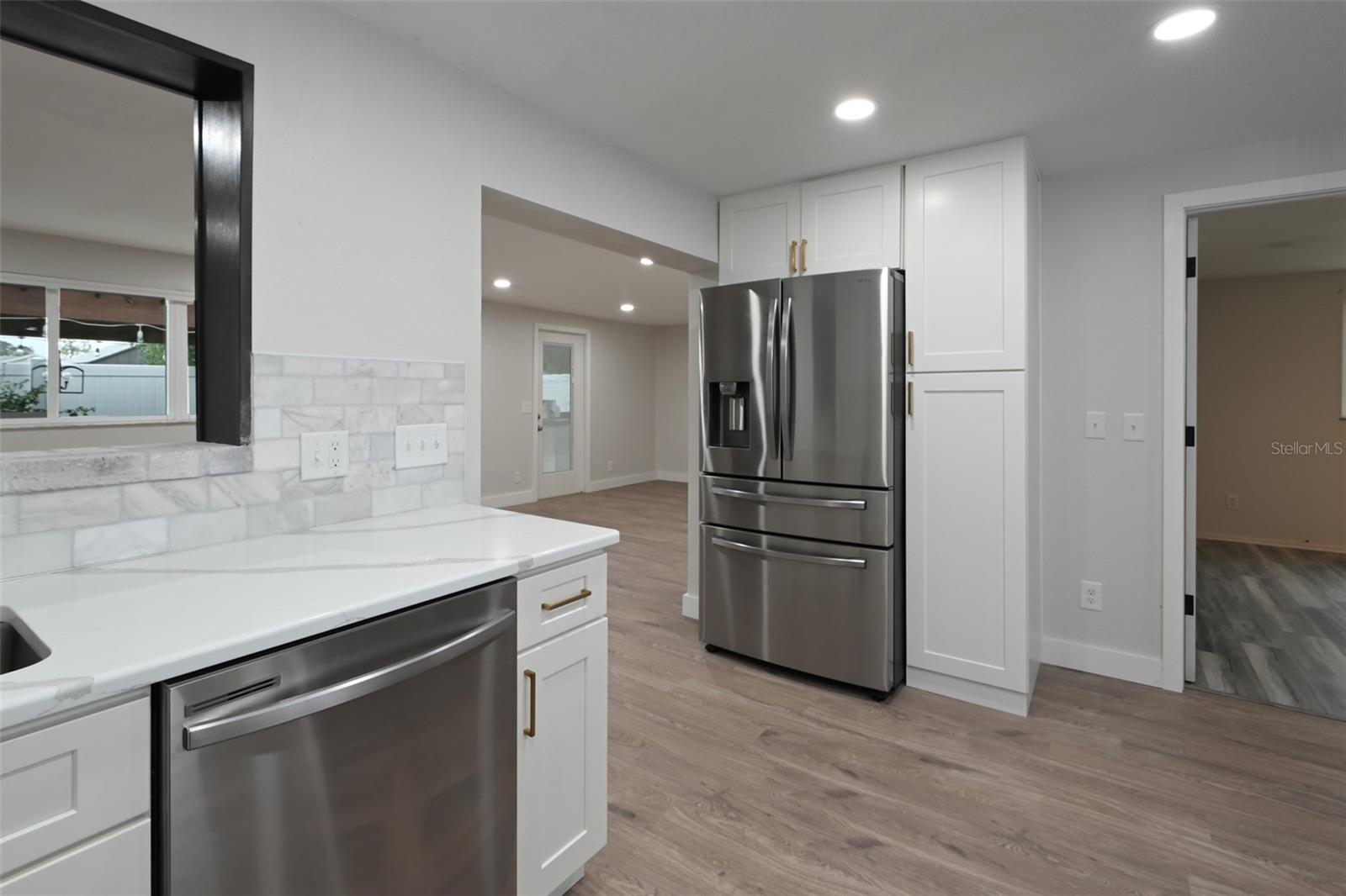 Kitchen with beautiful quartz countertops, newer stainless appliances, new flooring throughout home.