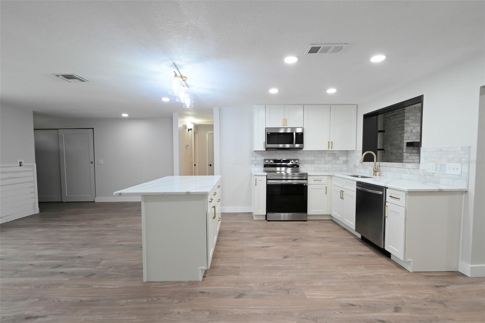 Inside kitchen area with new stainless appliances, quartz countertops and quartz island.