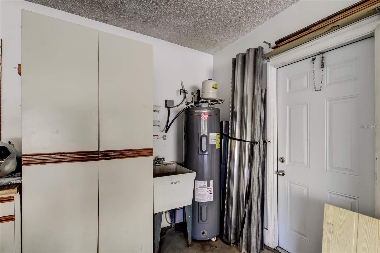 54. Storage Cabinets, Utility Sink, Hurricane Shutters Stored Nicely in Garage-Side Door to Garbage Cans Access