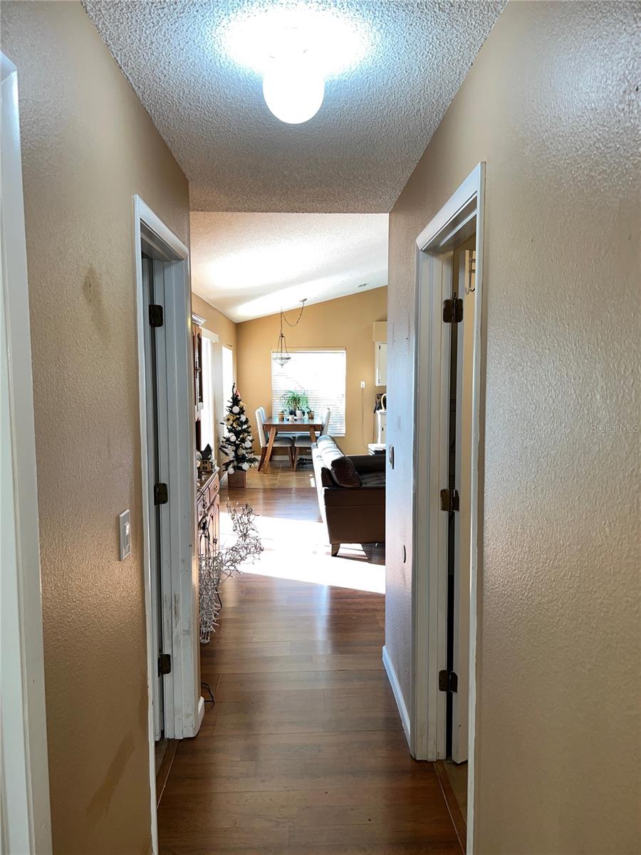 Hallway leading back to family room. Door on near left is to second bedroom. Door on far left is to hall bath. Door on right is to laundry room.