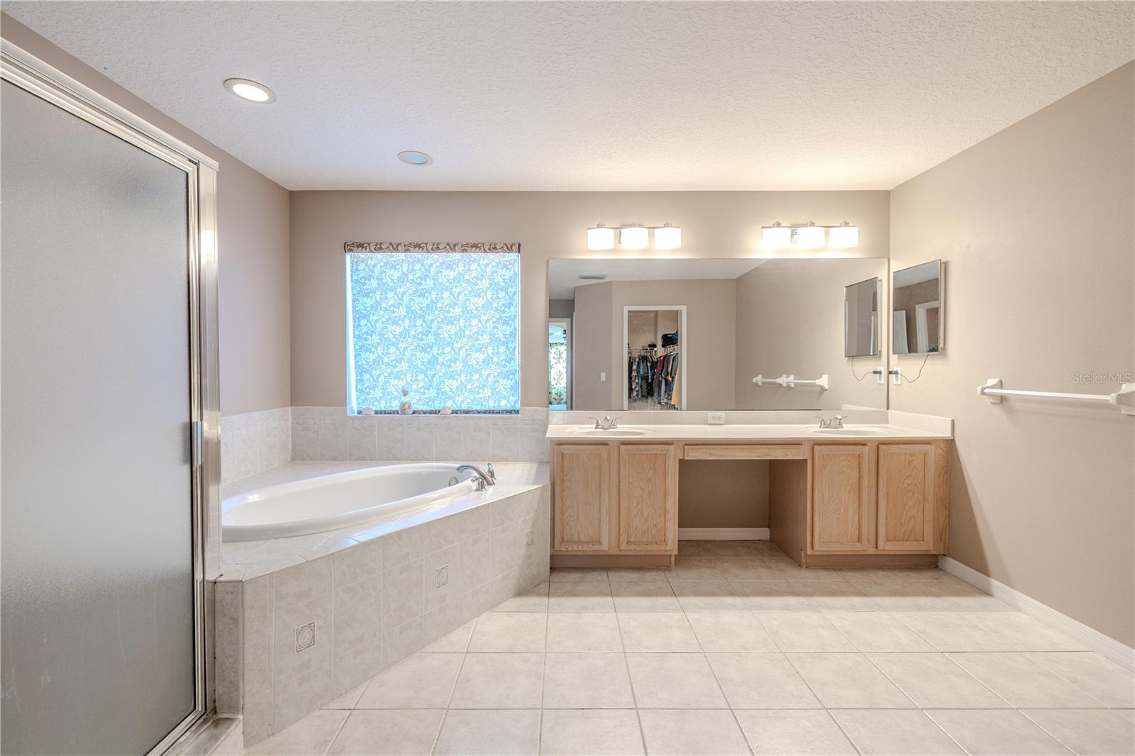 Spacious primary en-suite features a dual-sink vanity with makeup area, a relaxing soaking tub, and a separate shower—creating a true spa-like retreat.