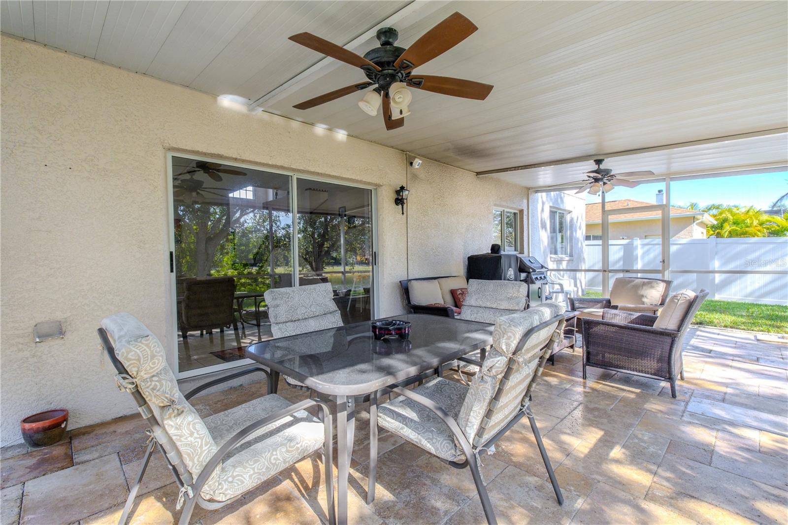 Spacious screened lanai features ceiling fans, paver flooring, and plenty of room for outdoor dining and lounging—perfect for entertaining year-round.