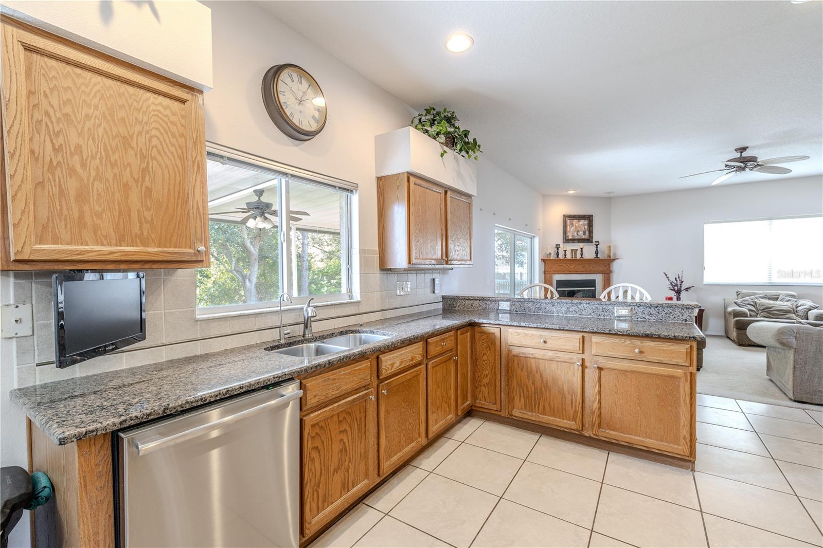Open kitchen features granite countertops, abundant cabinetry, and a large breakfast bar, all overlooking the family room and offering backyard views through the sink window.