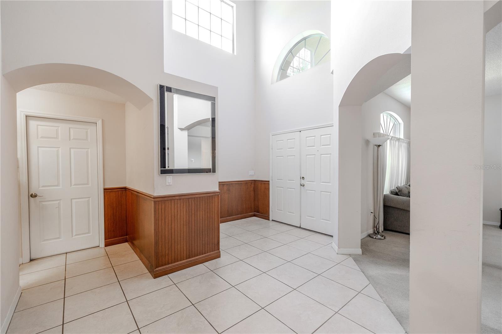 Soaring two-story foyer features tile flooring, arched entryways, and abundant natural light, garage entry, creating a bright and welcoming first impression.