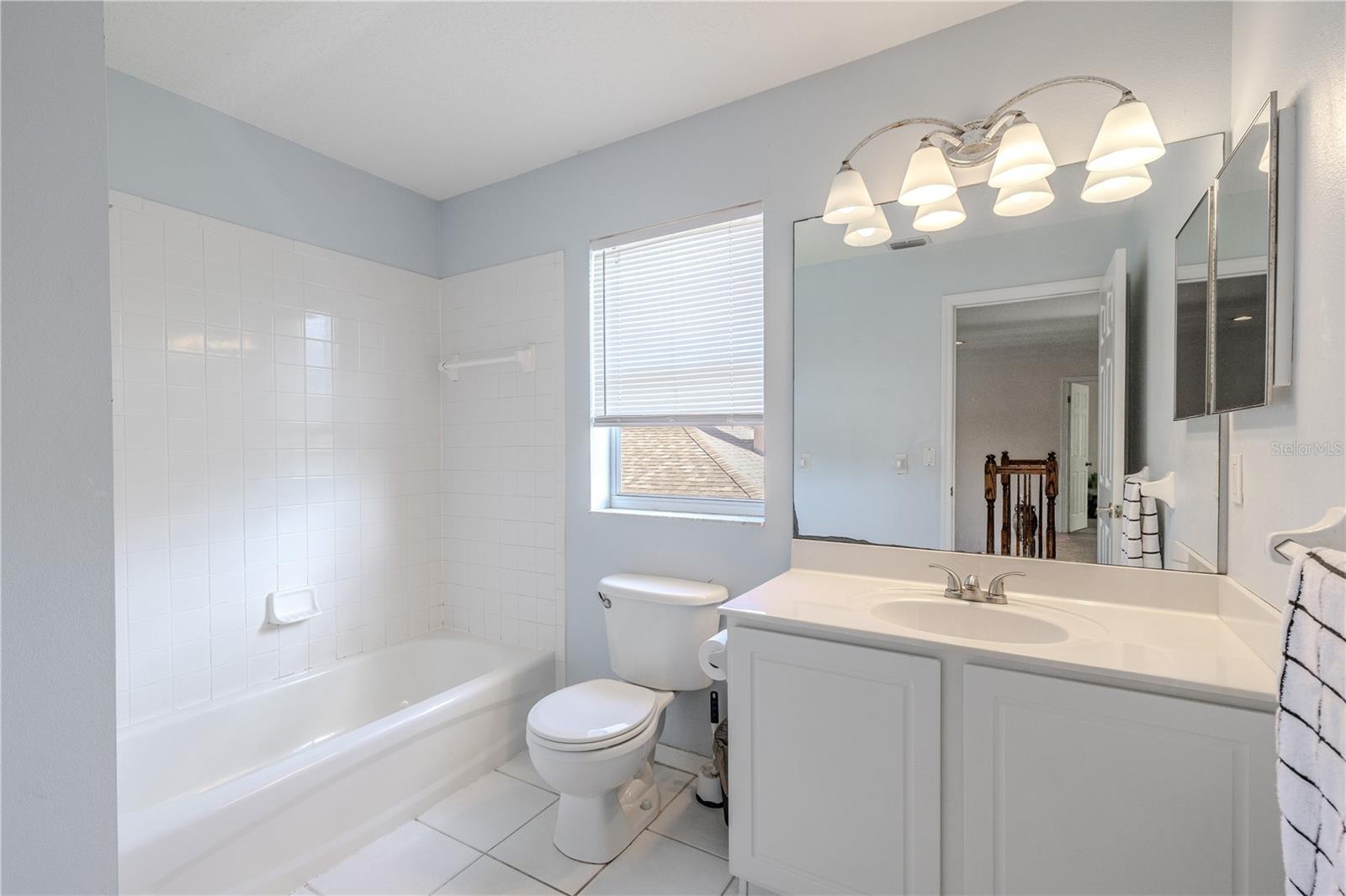 Third full bathroom features a clean tub/shower combo, bright vanity with ample counter space, and a window that brings in natural light.