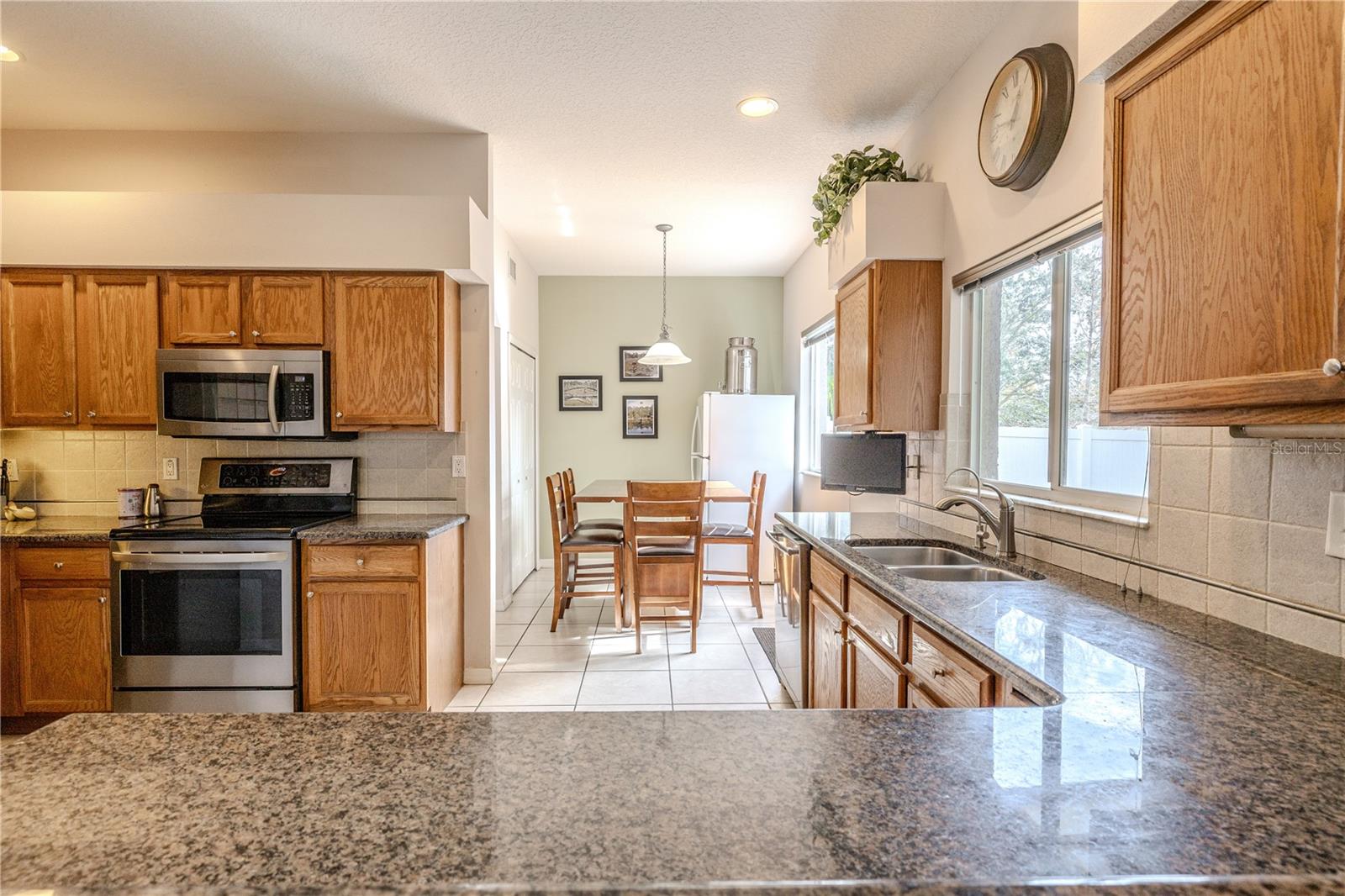 Sunlit kitchen showcases granite counters, stainless appliances, and ample cabinetry, flowing into a cozy breakfast nook with windows and a sliding door for easy indoor-outdoor dining.
