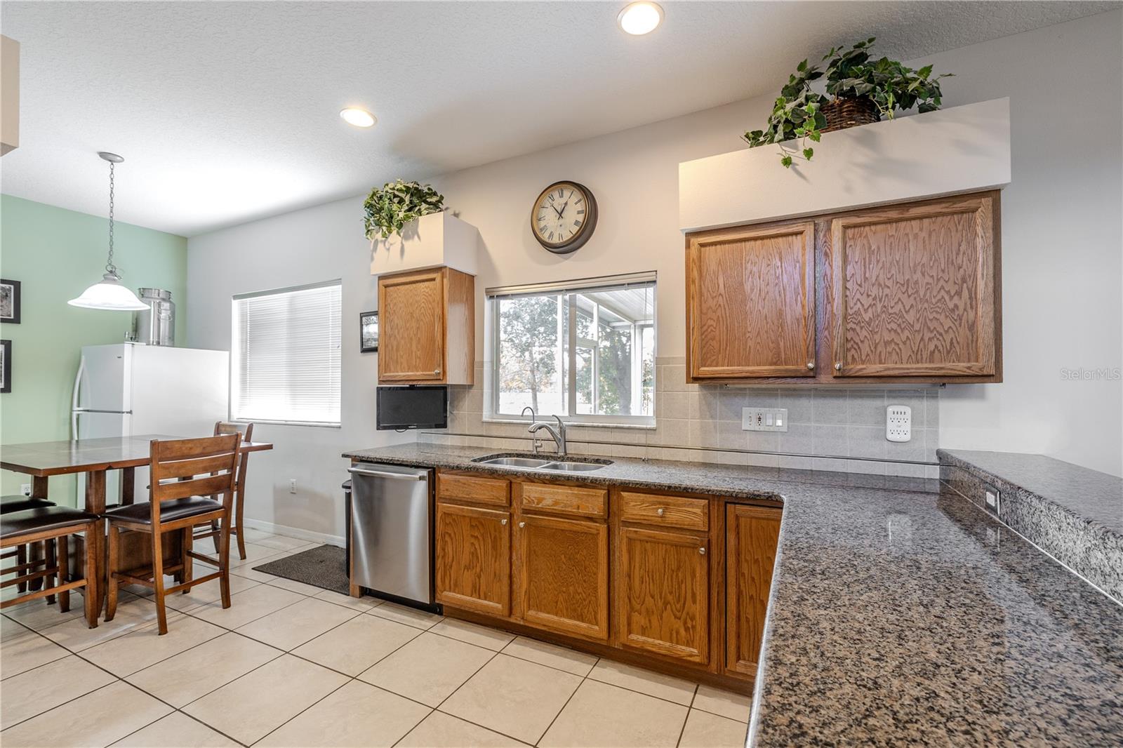 Spacious eat-in kitchen features granite countertops, abundant cabinetry, and a bright dinette area, with a window over the sink offering lovely views to the lanai and backyard.