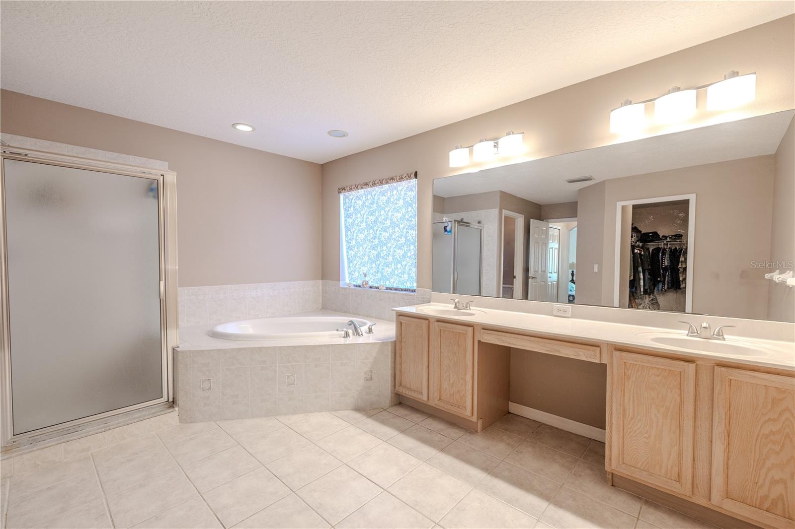 Primary bath impresses with a huge dual-sink vanity, separate shower, and a corner soaking tub, plus direct access to the walk-in closet for added convenience.